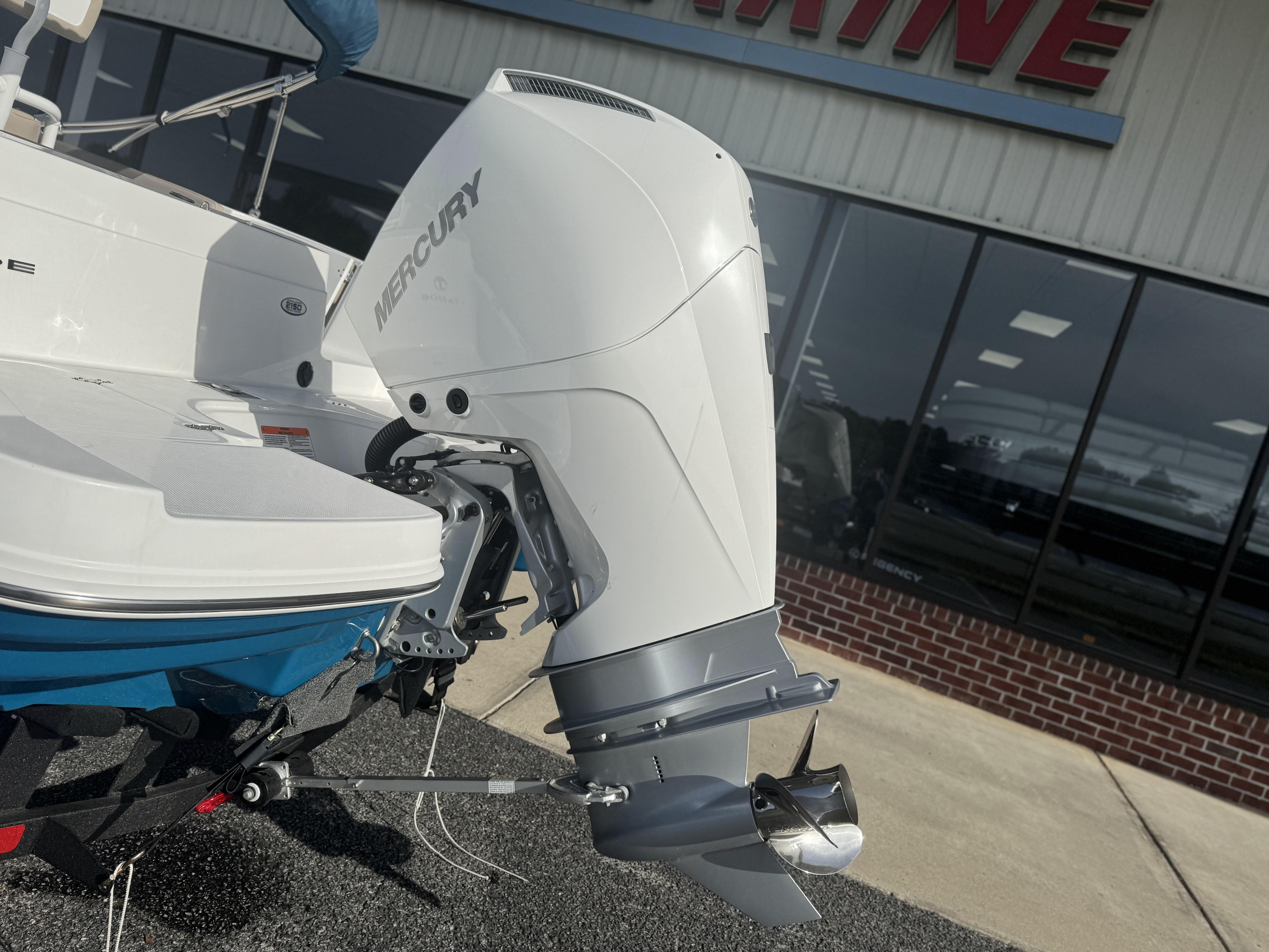 2025 Tahoe 2150 CC boat with Mercury outboard motor displayed outside a showroom.