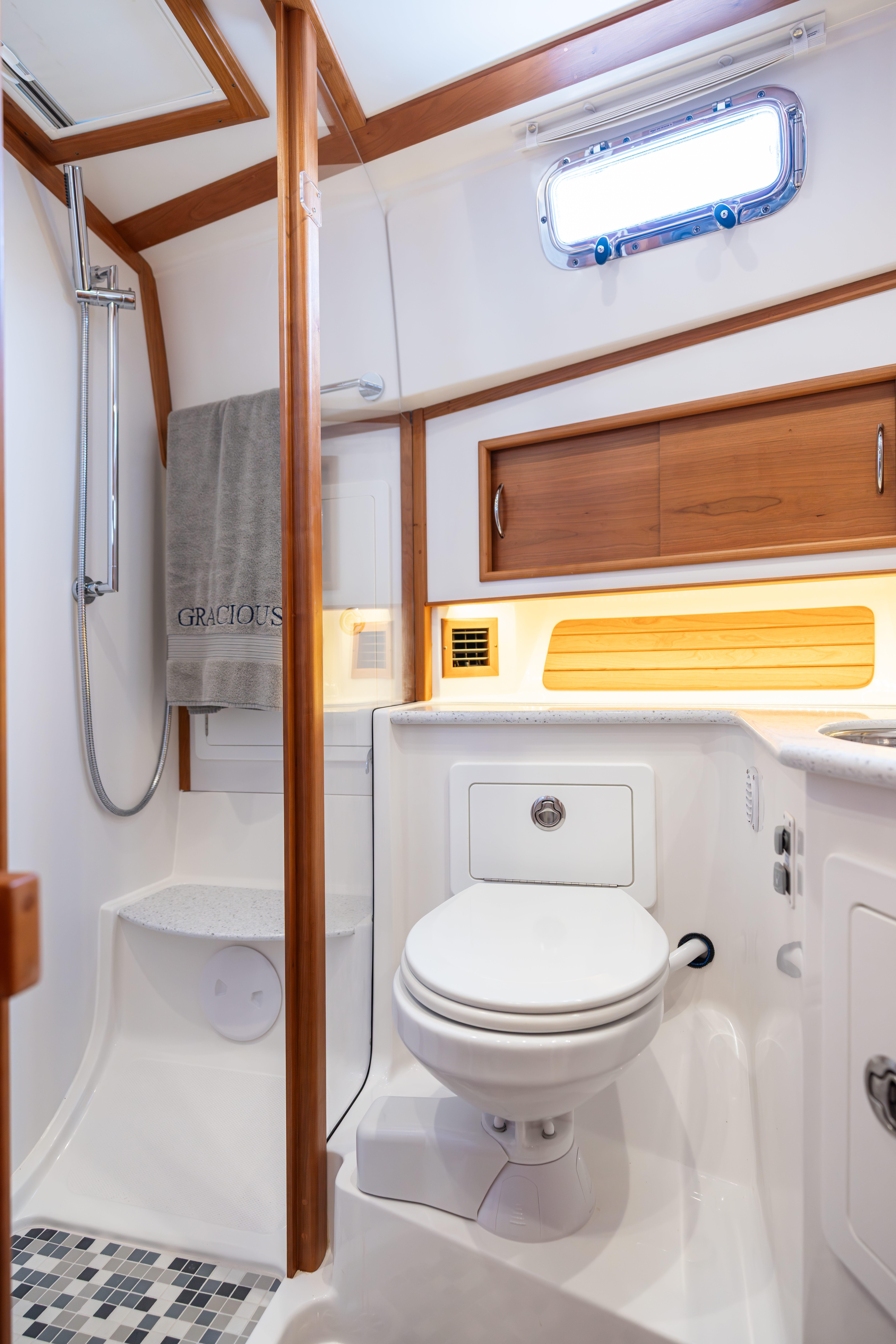 2020 Sabre 48 Salon Express bathroom with shower, toilet, and wooden cabinetry.