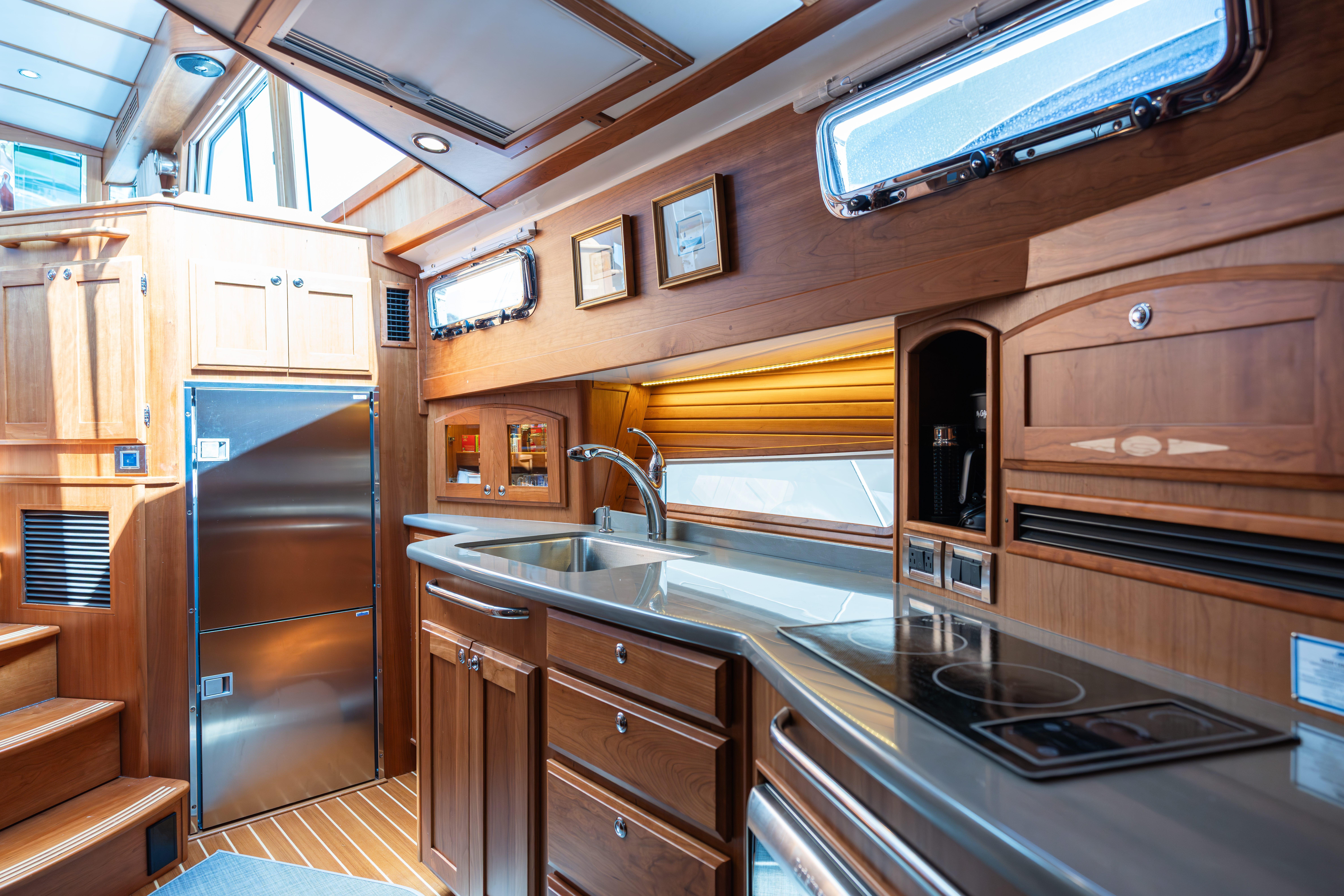 Luxurious interior of 2020 Sabre 48 Salon Express yacht kitchen with wood cabinetry and modern appliances.