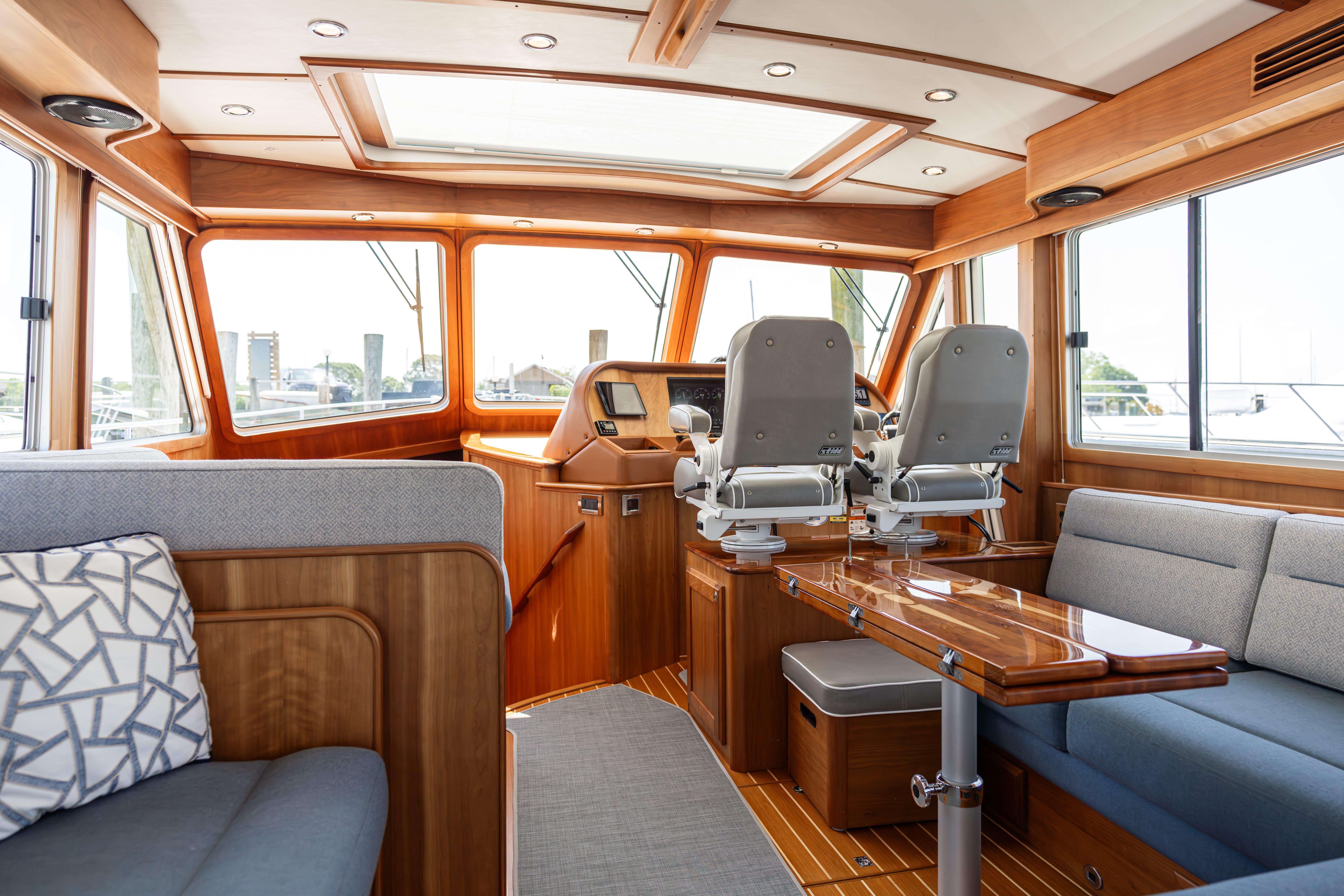 2020 Sabre 48 Salon Express interior with helm chairs, wooden table, and panoramic windows.