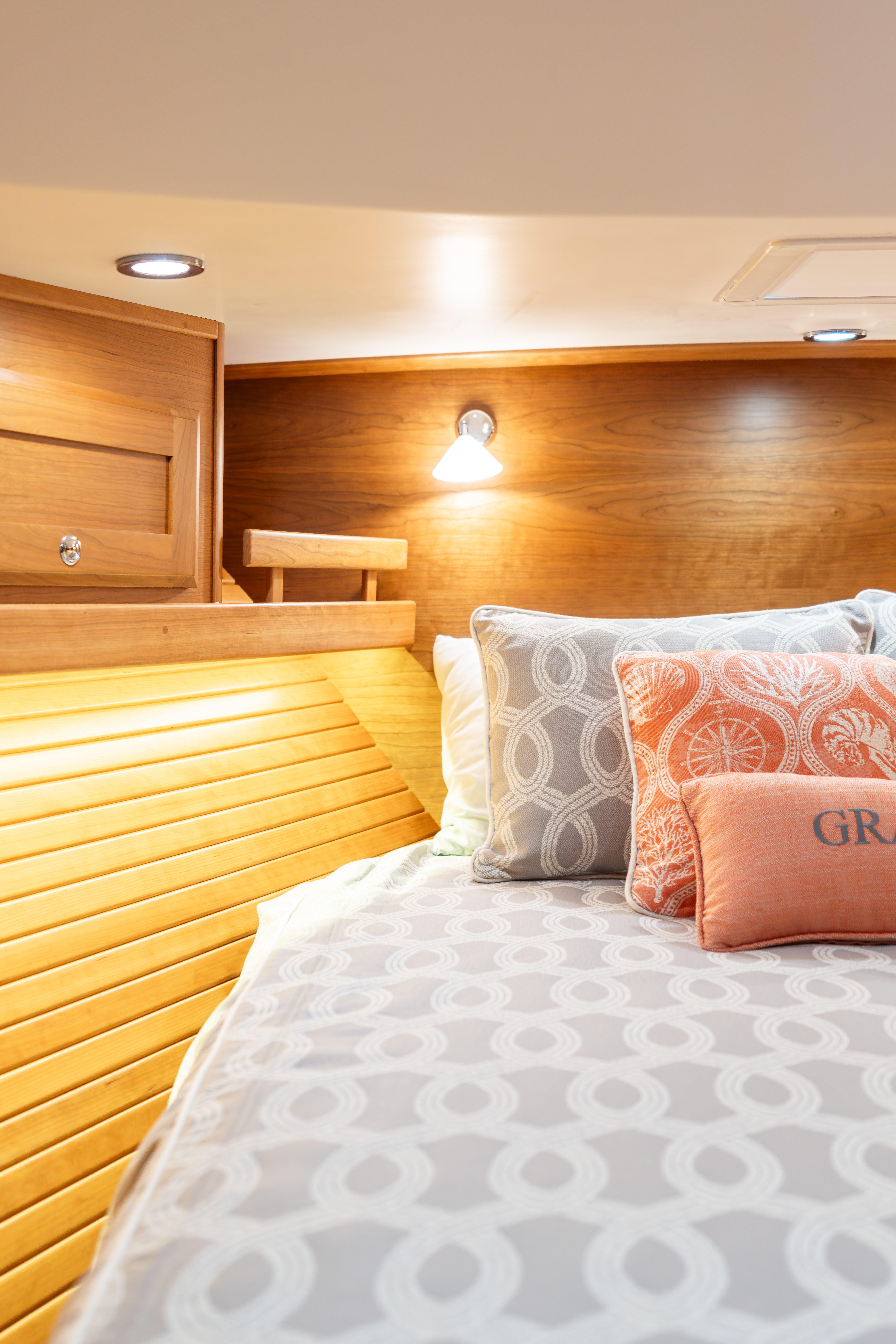 Cozy cabin interior of 2020 Sabre 48 Salon Express with elegant bedding and warm lighting.