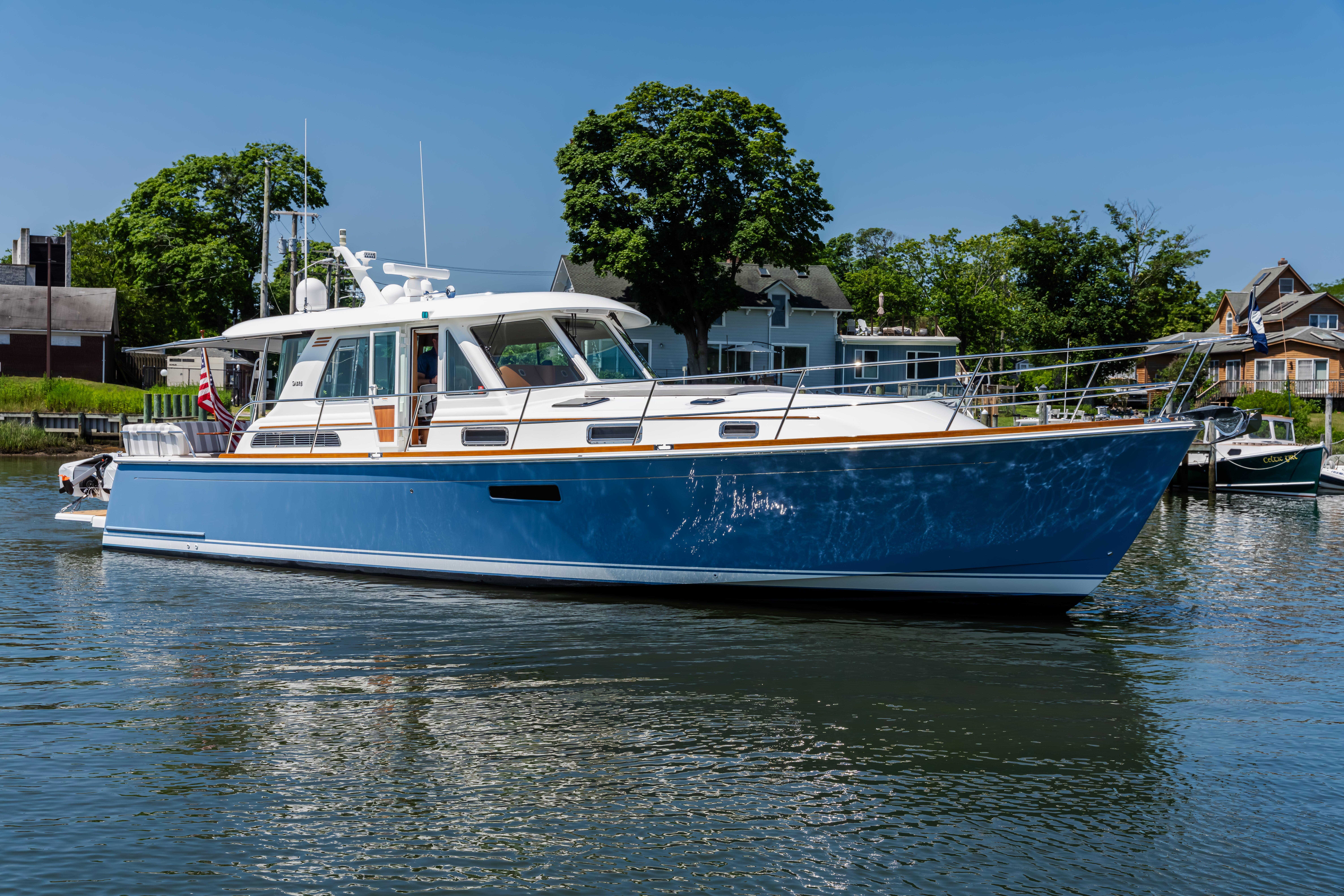 2020 Sabre 48 Salon Express yacht on calm water, surrounded by trees and houses.
