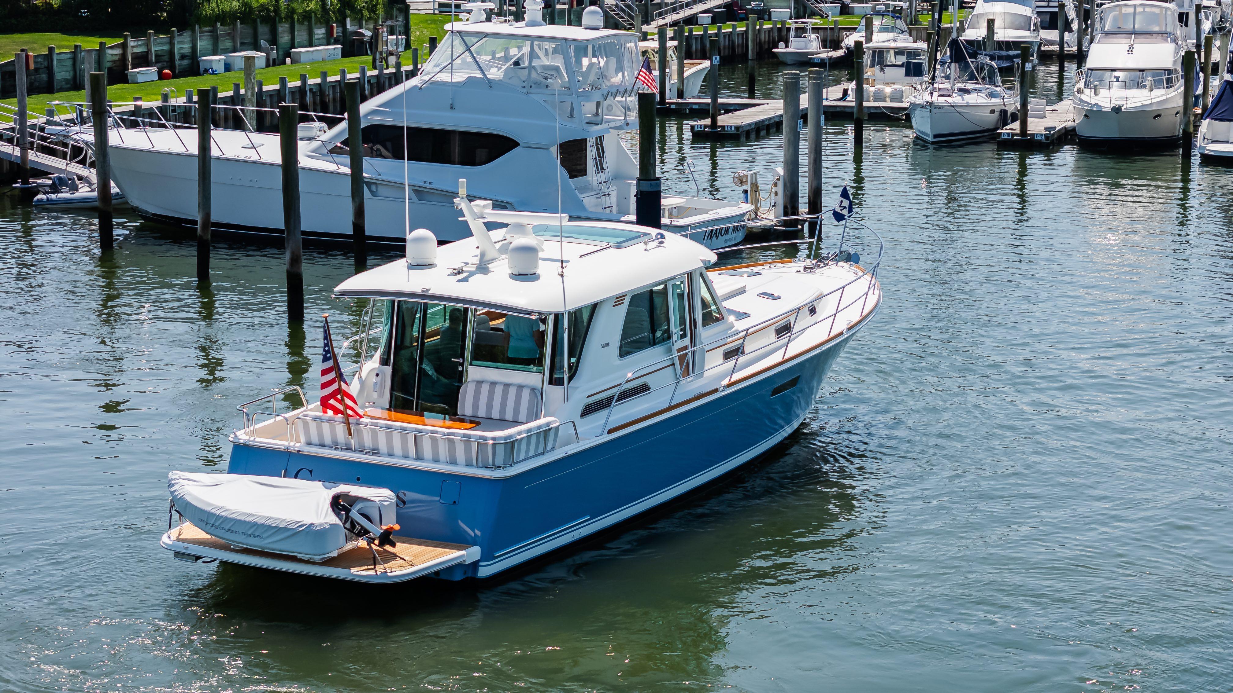 2020 Sabre 48 Salon Express yacht docked in a marina, surrounded by other boats.