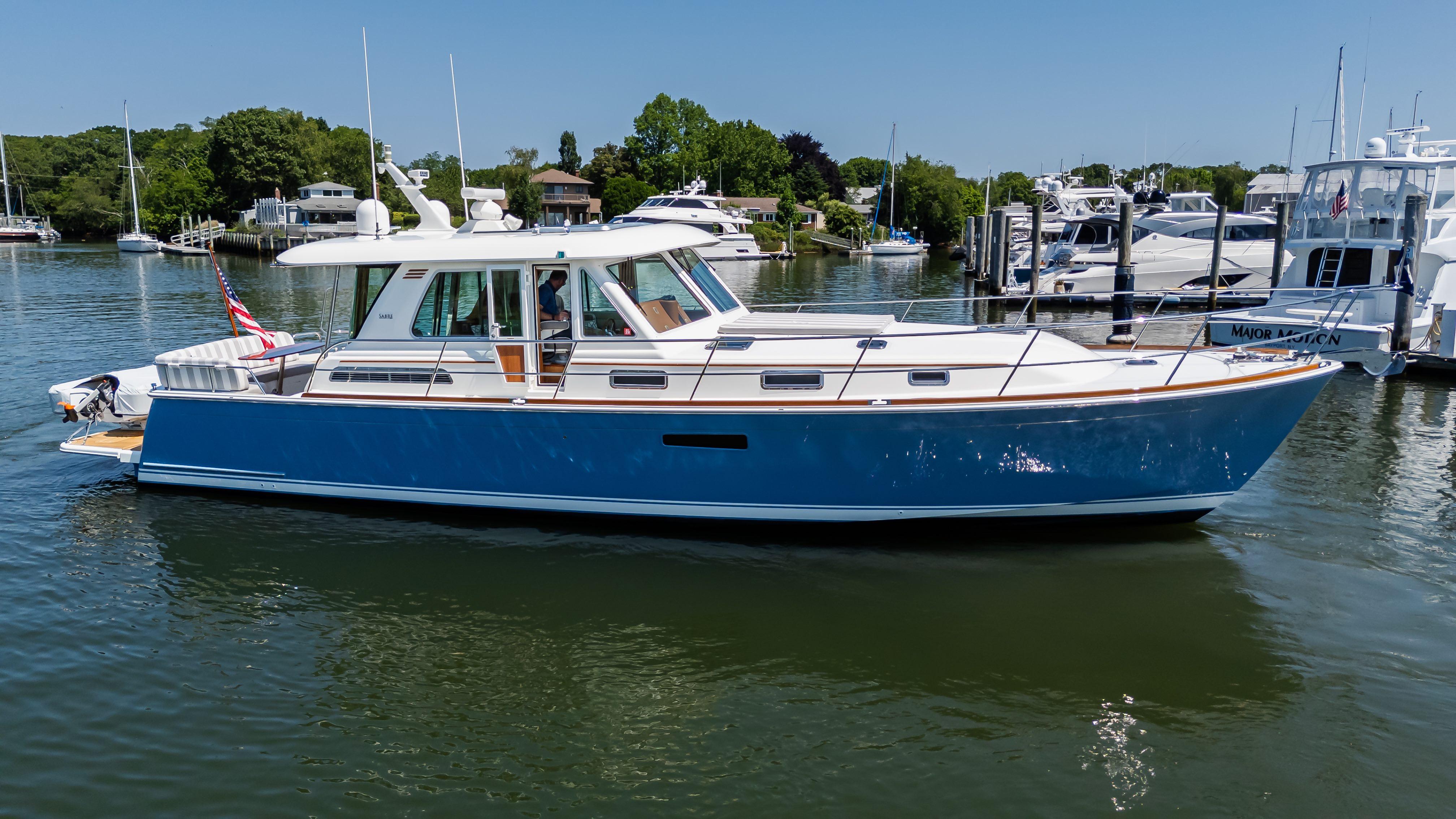 2020 Sabre 48 Salon Express yacht on calm water, surrounded by greenery and other boats.