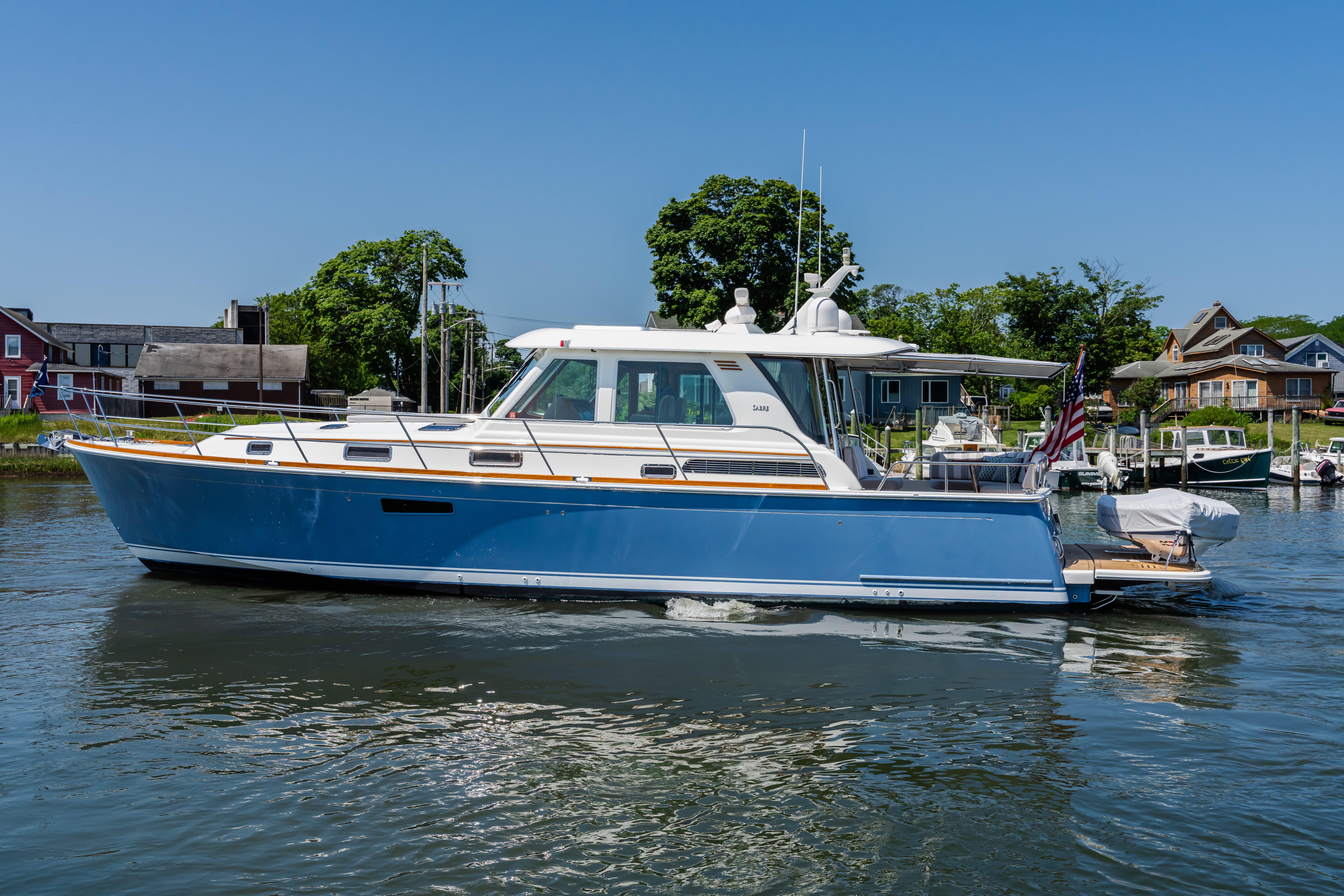 2020 Sabre 48 Salon Express yacht cruising on a sunny day near waterfront homes.