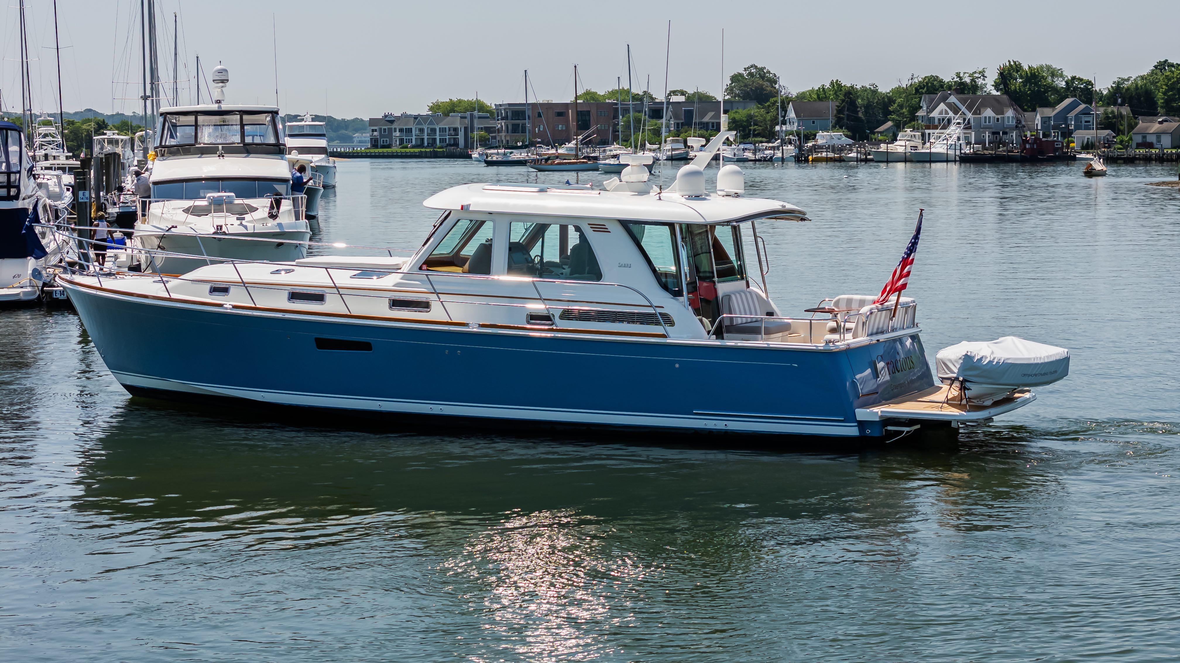 2020 Sabre 48 Salon Express yacht cruising in a marina with American flag.