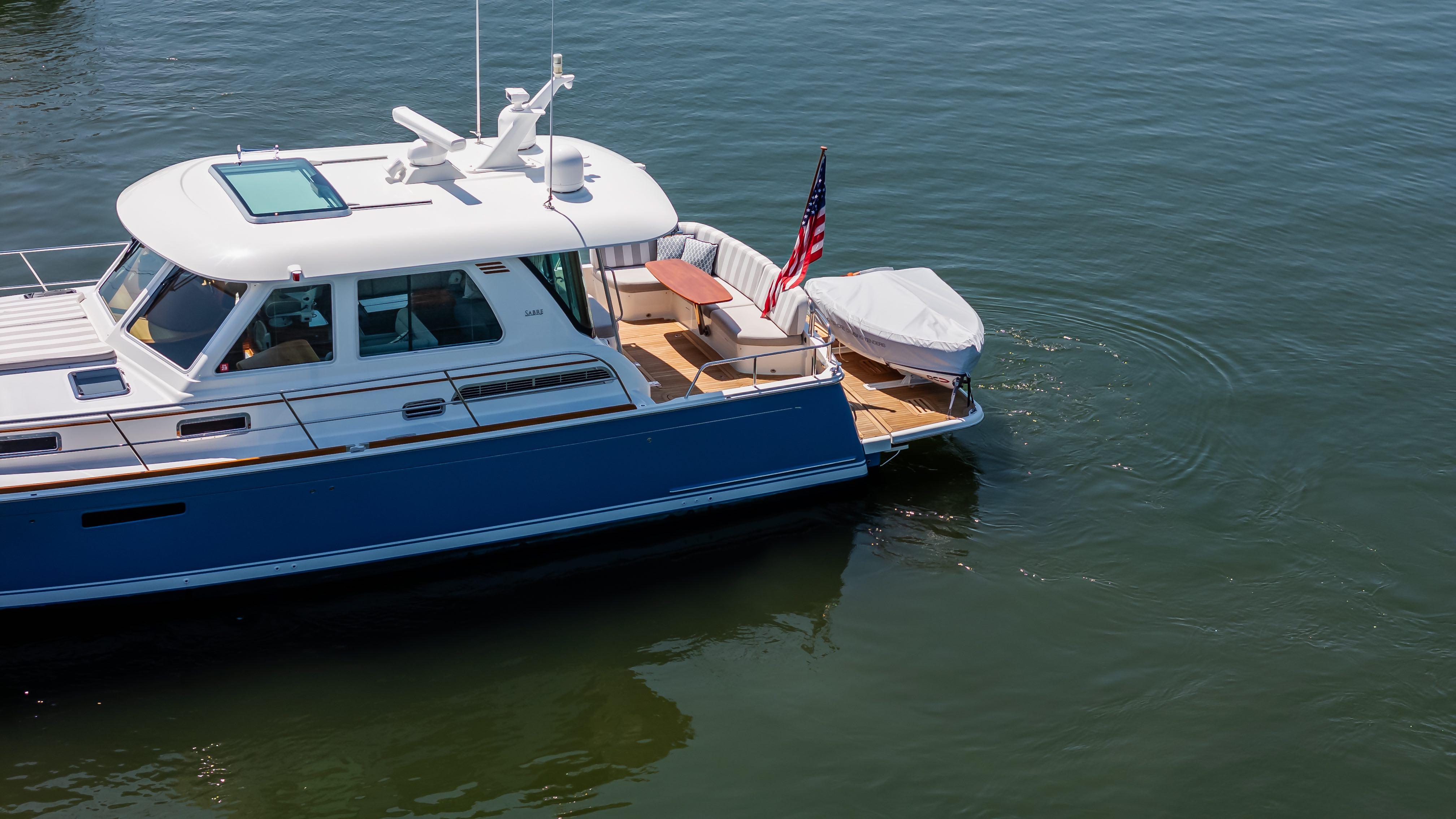 2020 Sabre 48 Salon Express yacht on calm water, featuring a sleek design and American flag.