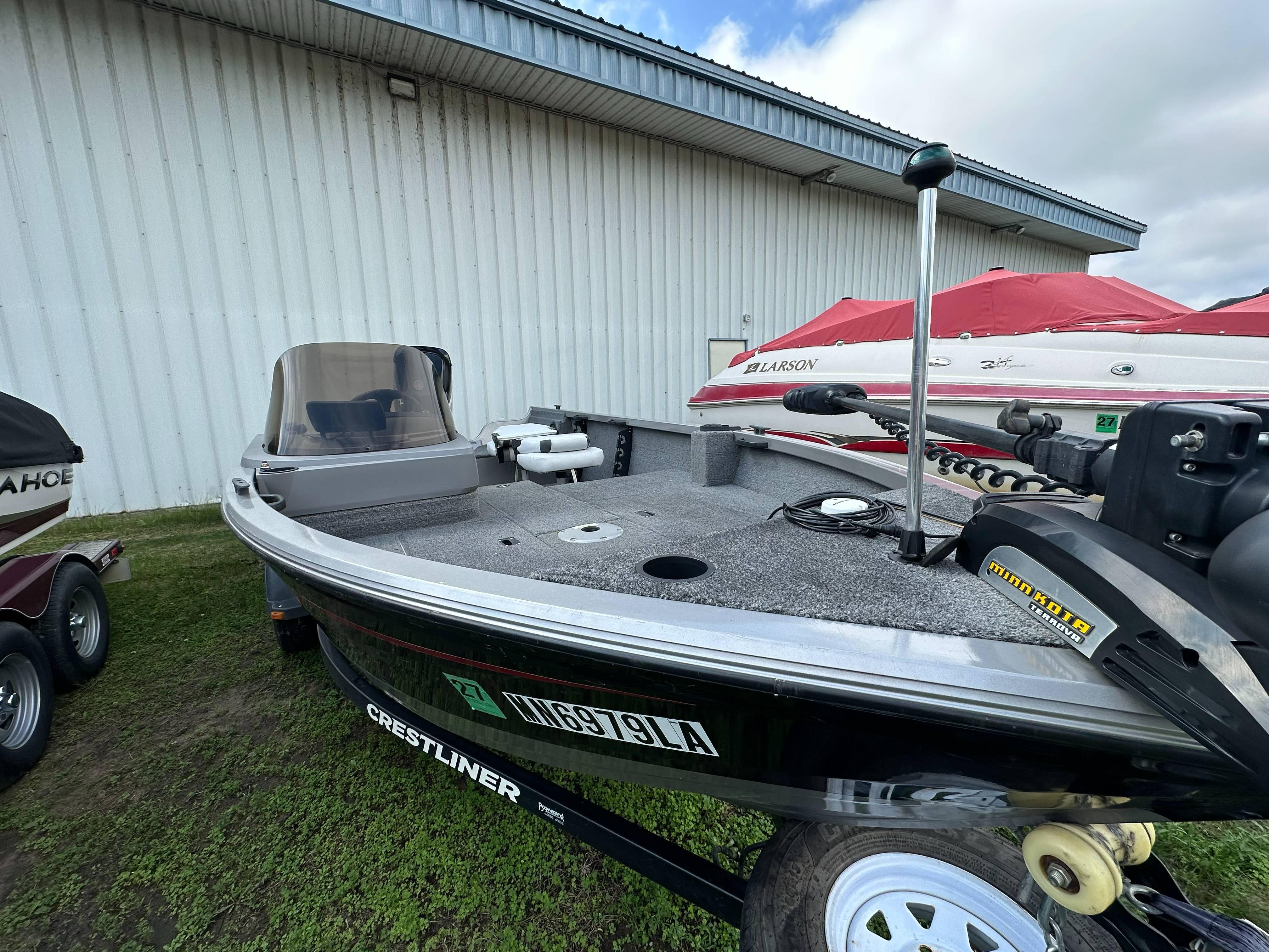 2013 Crestliner Fish Hawk 1650 SC boat on trailer, parked near a building.