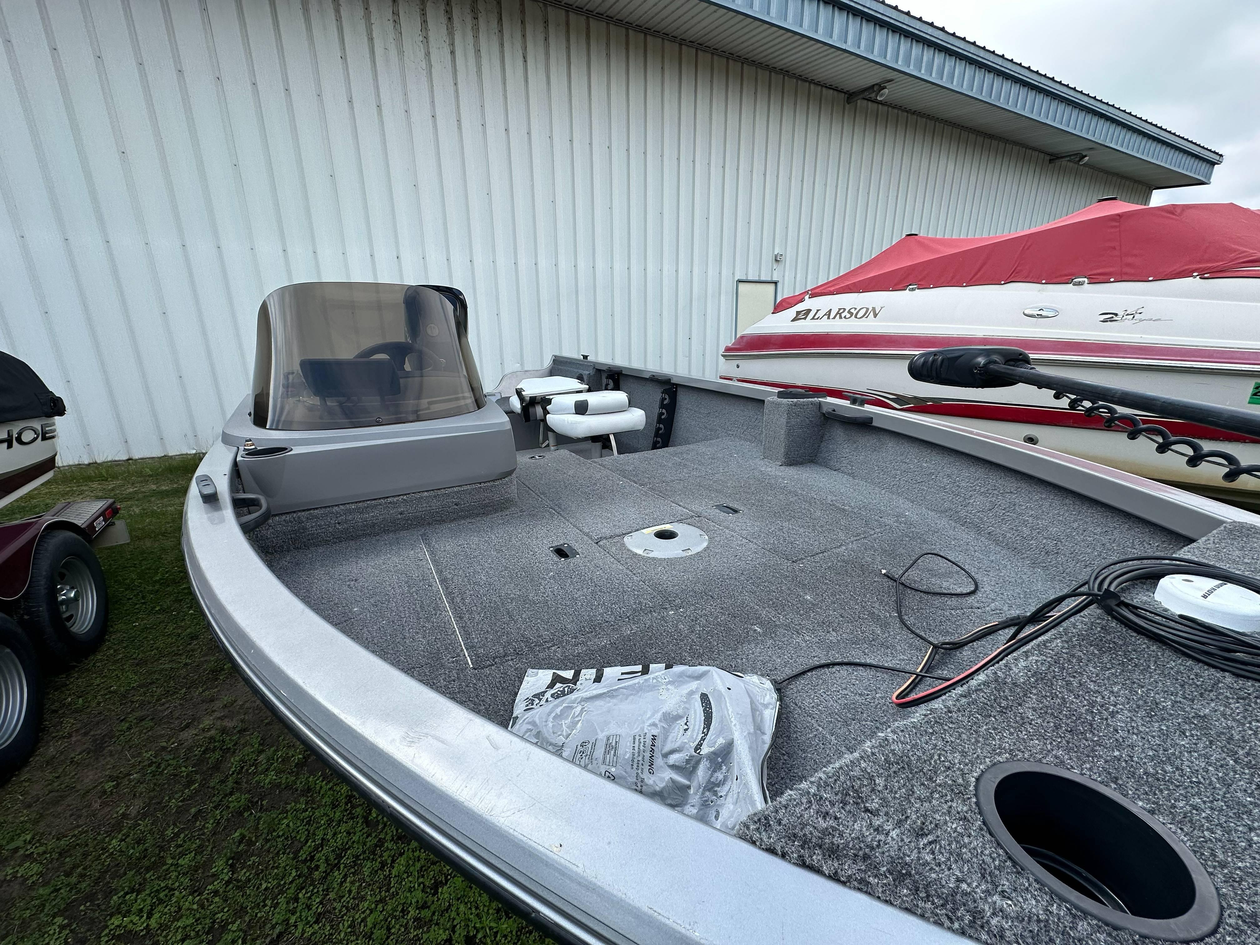 2013 Crestliner Fish Hawk 1650 SC boat with spacious deck, parked near a white building.