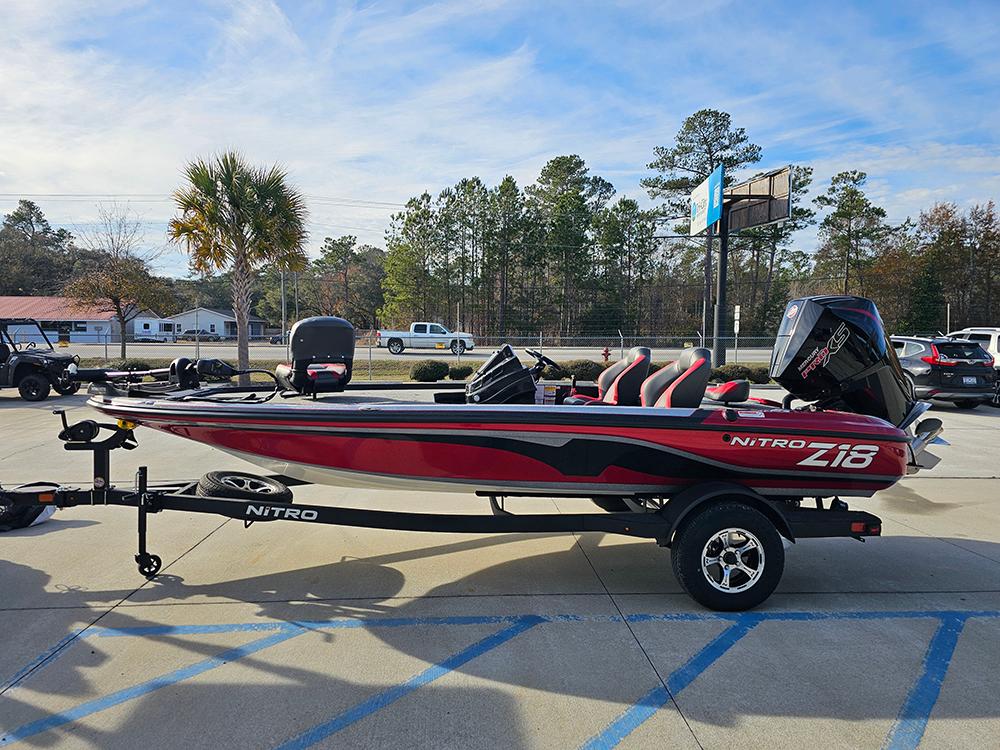 2025 Nitro Z18 boat in parking lot, red and black design, clear sky background.
