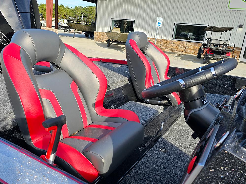 2025 Nitro Z18 boat interior with red and gray seats, steering wheel, and outdoor setting.