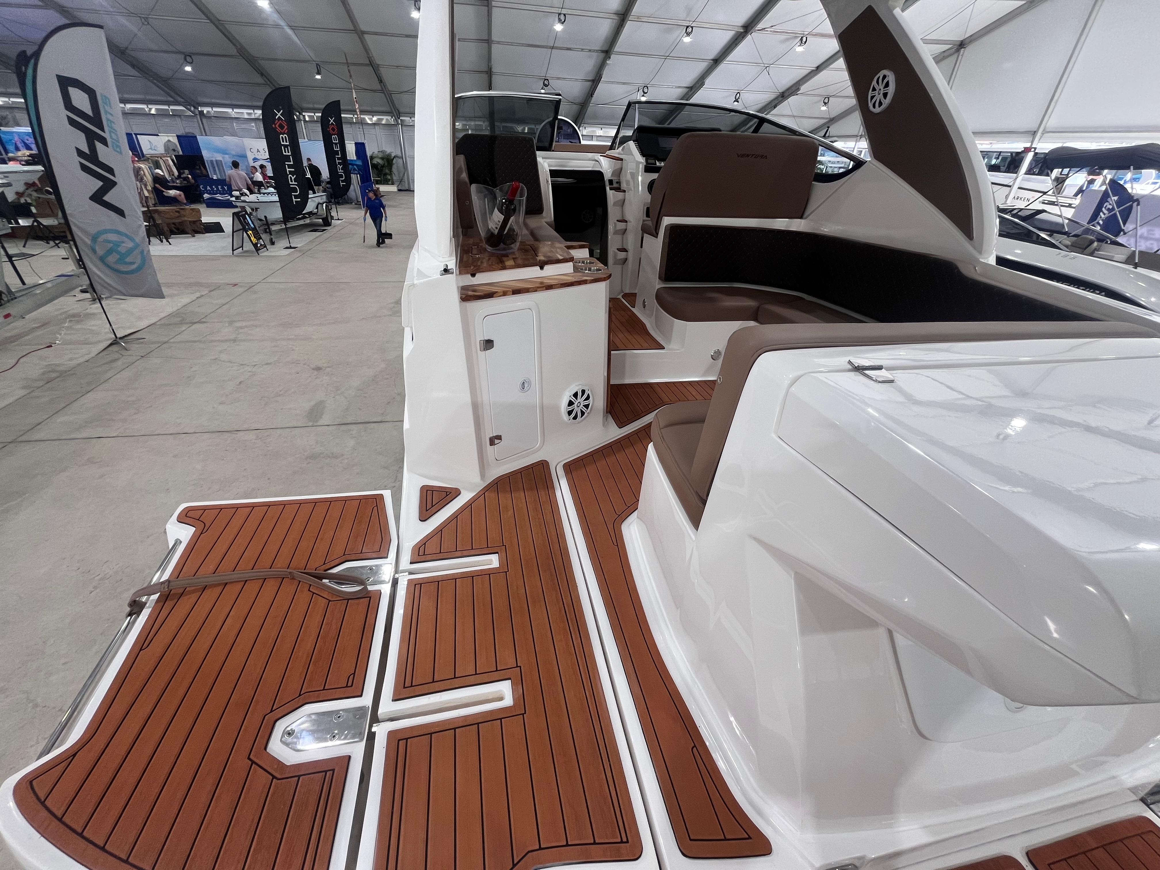 Ventura-DayCruiser 2025 -FL-US-2025 Ventura DayCruiser boat interior with teak flooring and cushioned seating at a boat show.-9681900 | Thumbnail