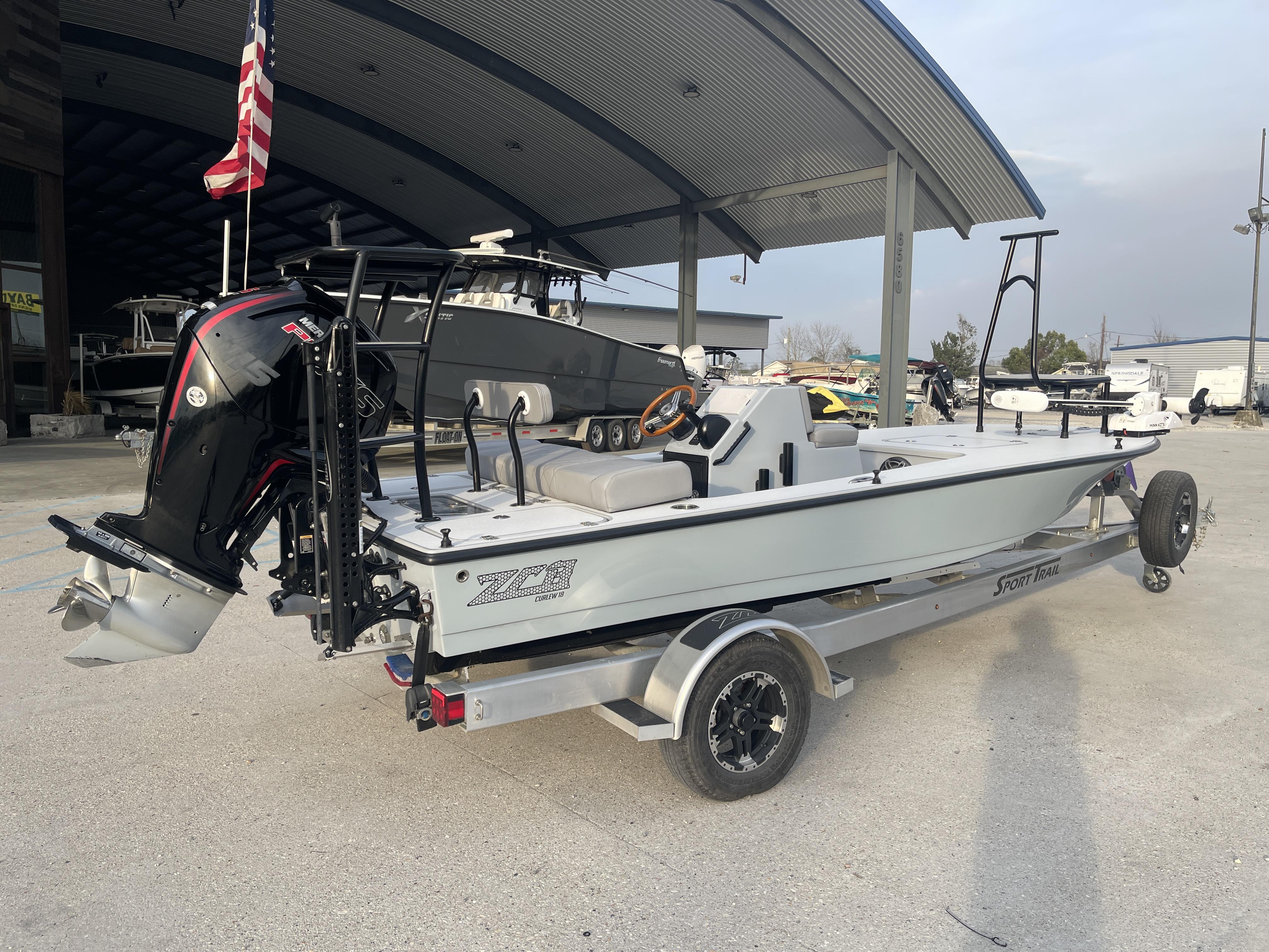 2023 ZCB 18 Curlew boat on trailer, parked outdoors under a metal canopy.