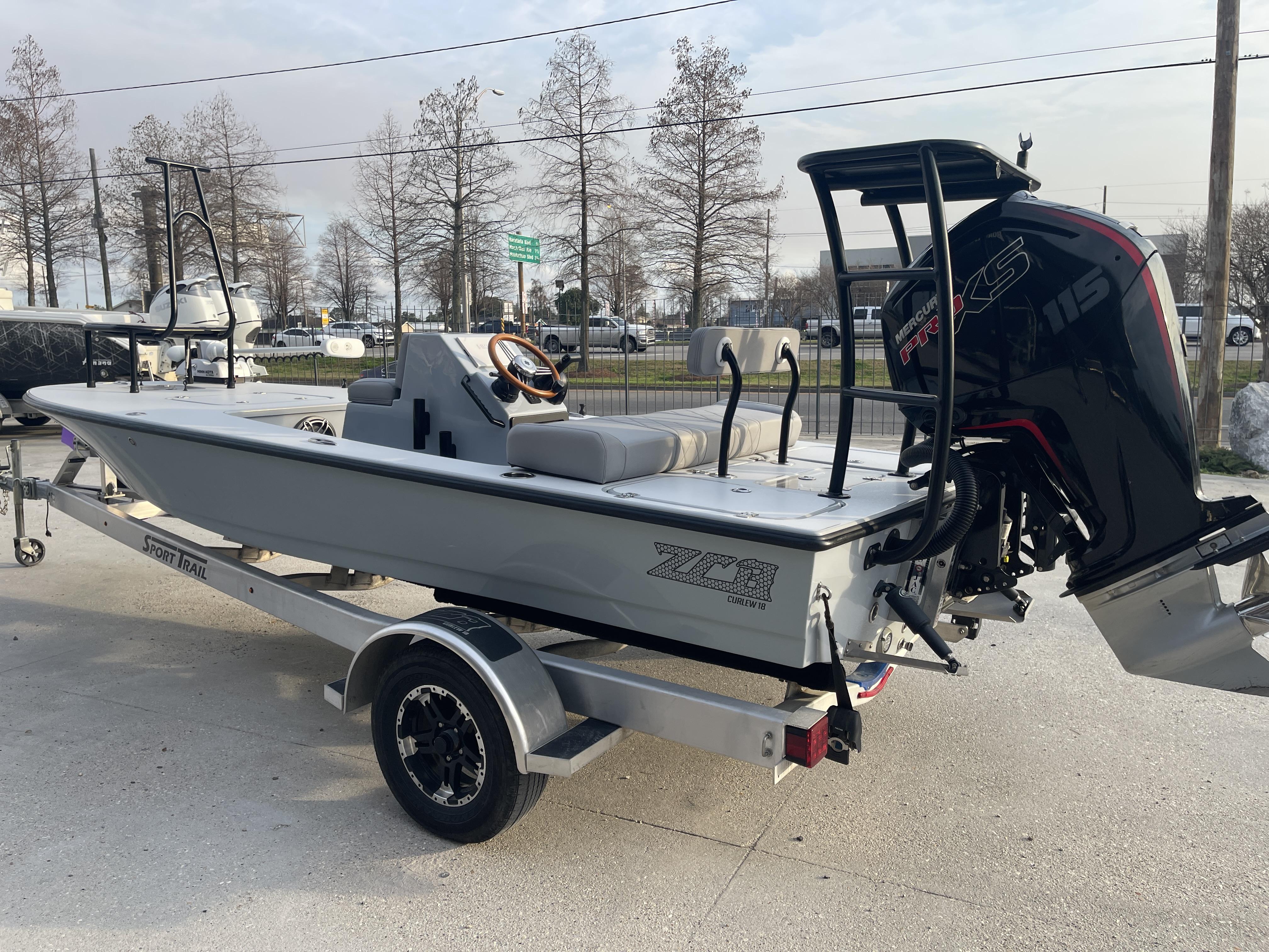2023 ZCB 18 Curlew boat on trailer with Mercury 115 engine, parked outdoors.