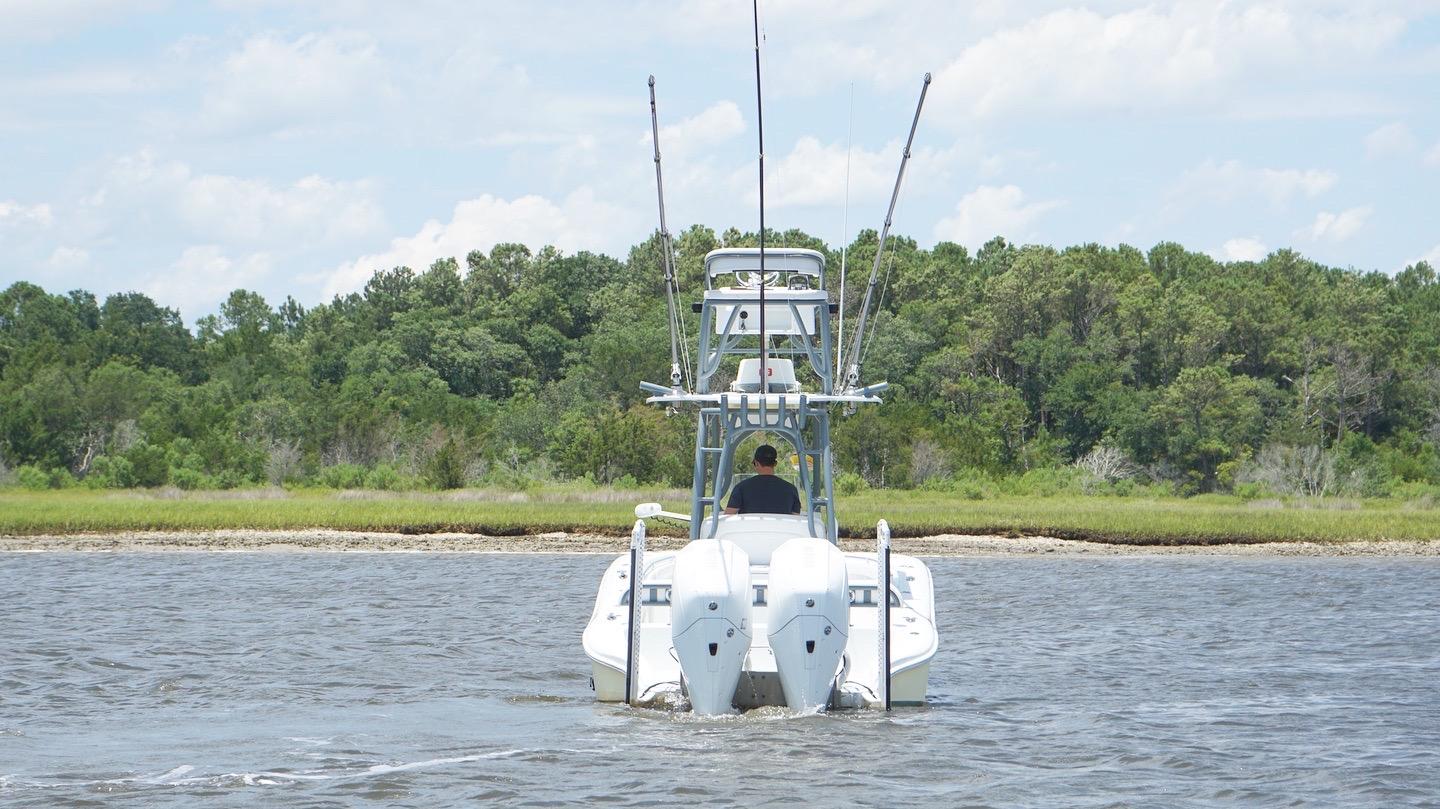 2020 Yellowfin 26 Hybrid boat navigating a river with lush green forest backdrop.