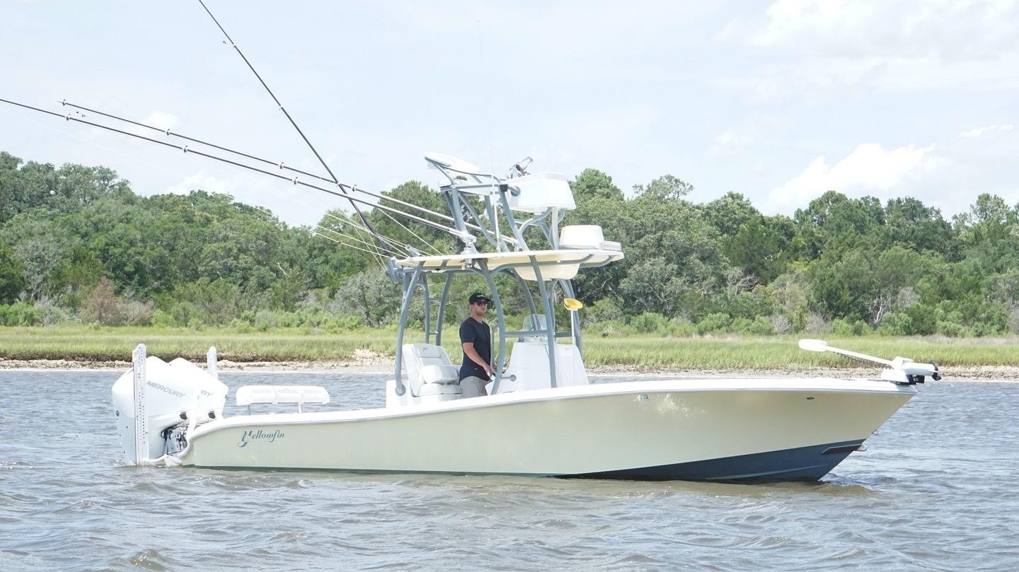 2020 Yellowfin 26 Hybrid boat on water, featuring fishing rods and lush green shoreline.