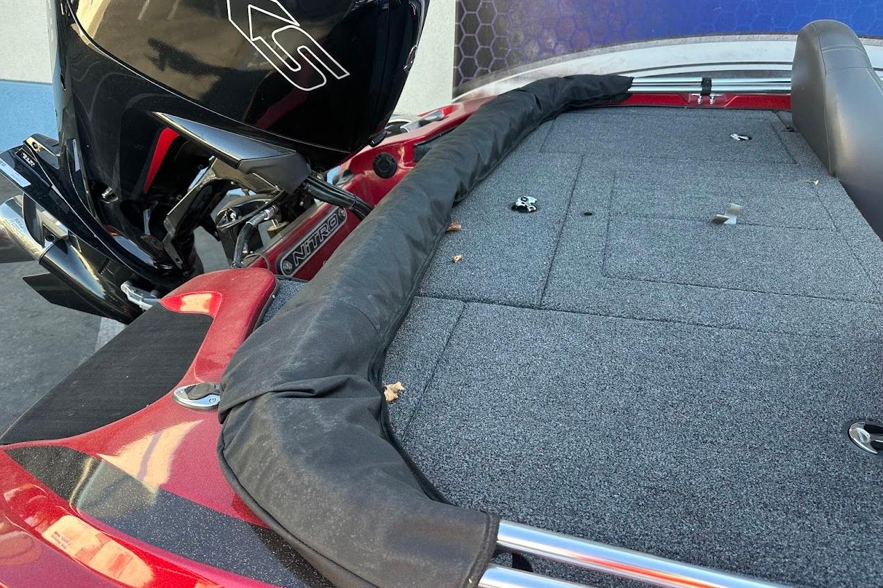 2024 Nitro Z17 boat deck with motor, featuring red accents and carpeted surface.