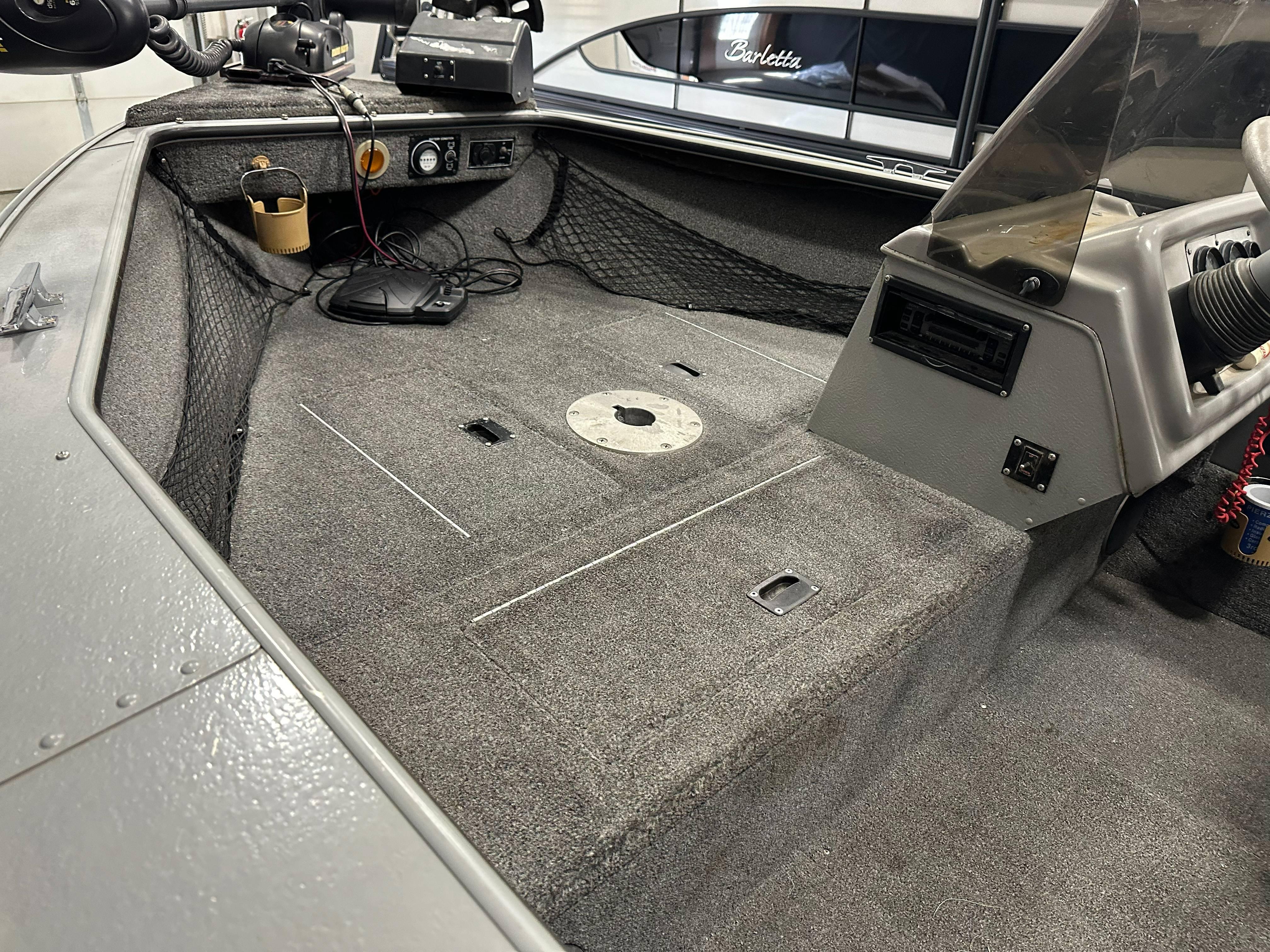 Interior of a 1995 Lund 1650 DLX boat with carpeted flooring and dashboard controls.