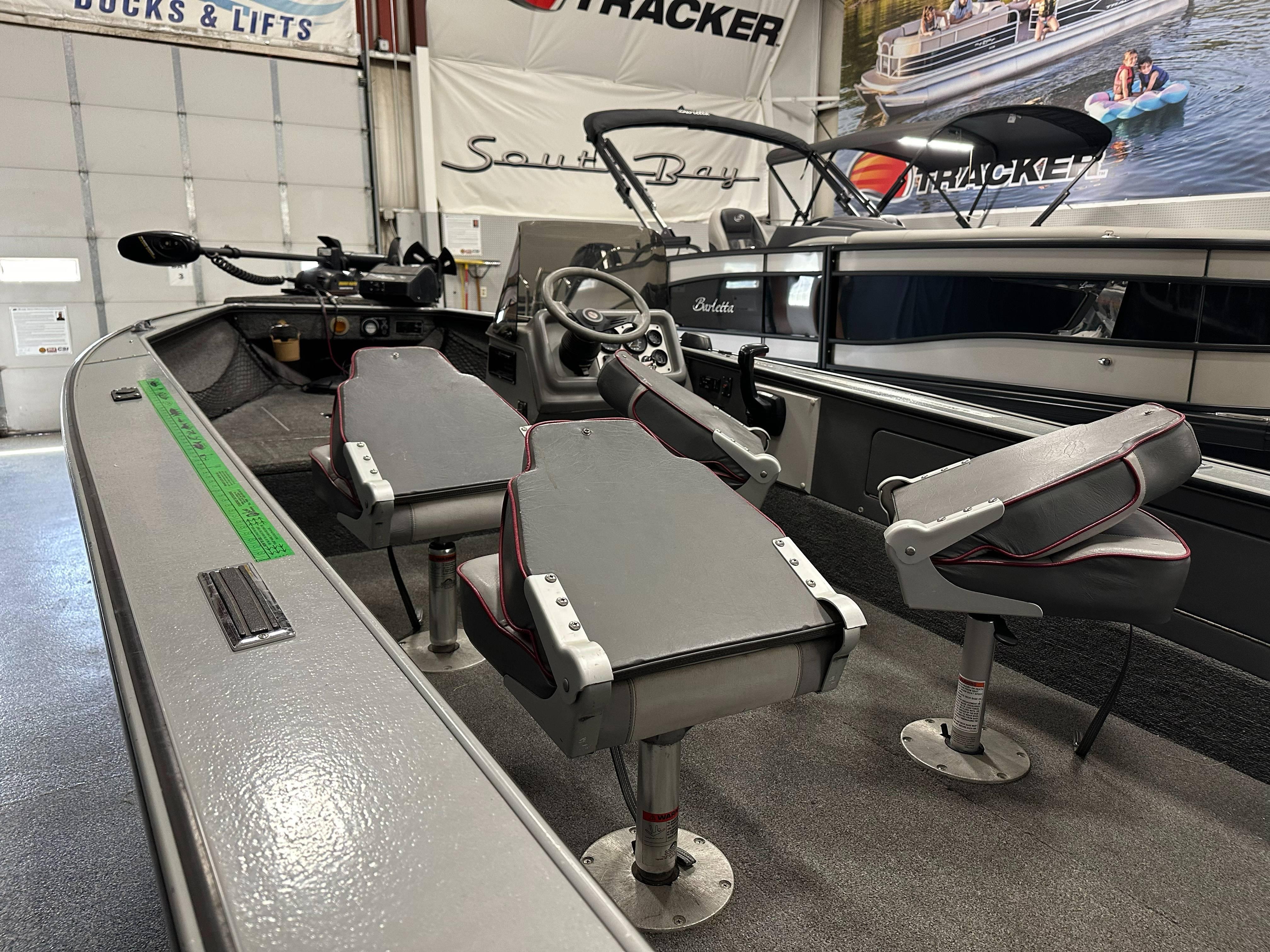 1995 Lund 1650 DLX boat interior with gray seating and steering wheel in showroom.