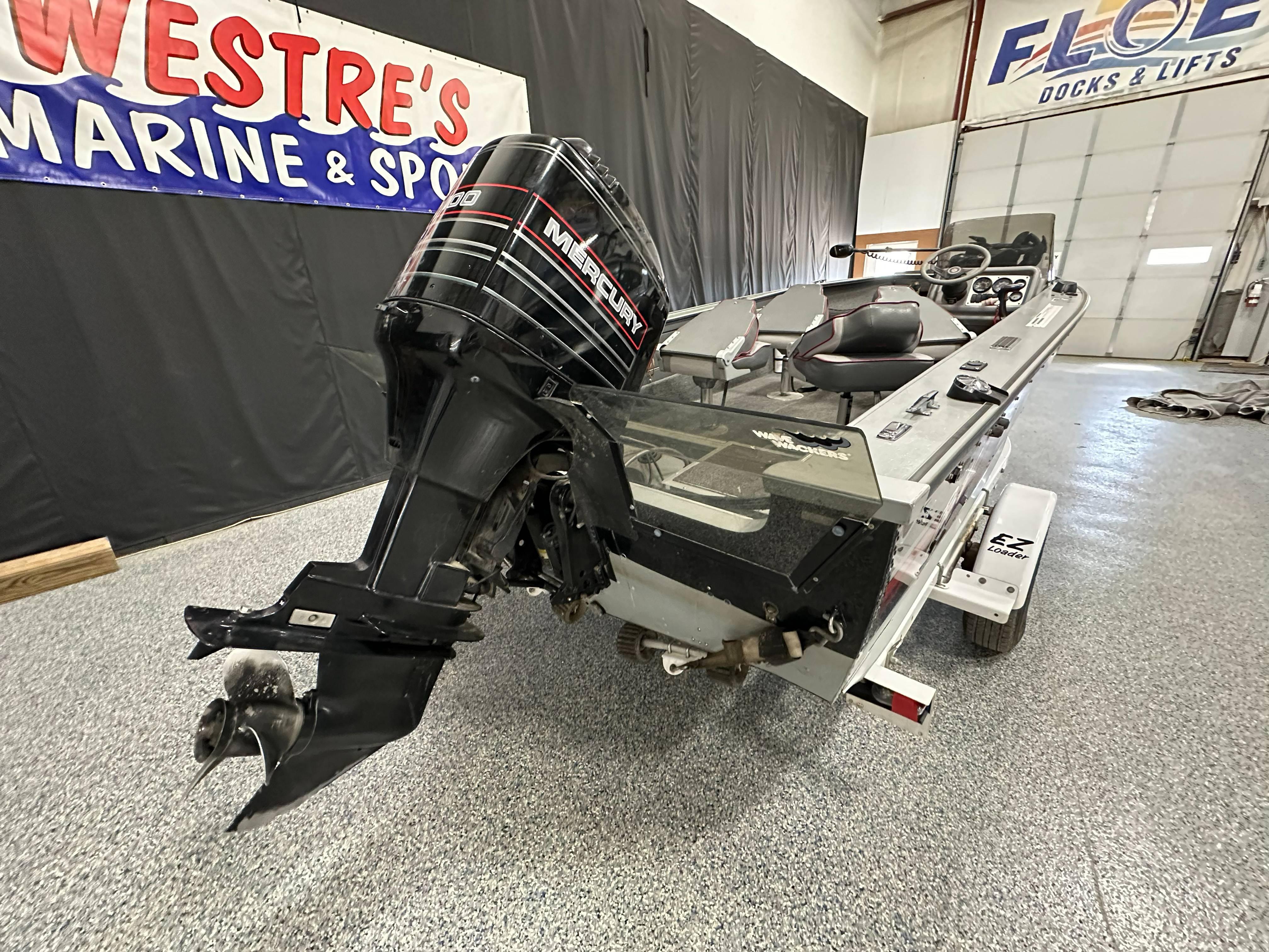 1995 Lund 1650 DLX boat with Mercury outboard motor in showroom.