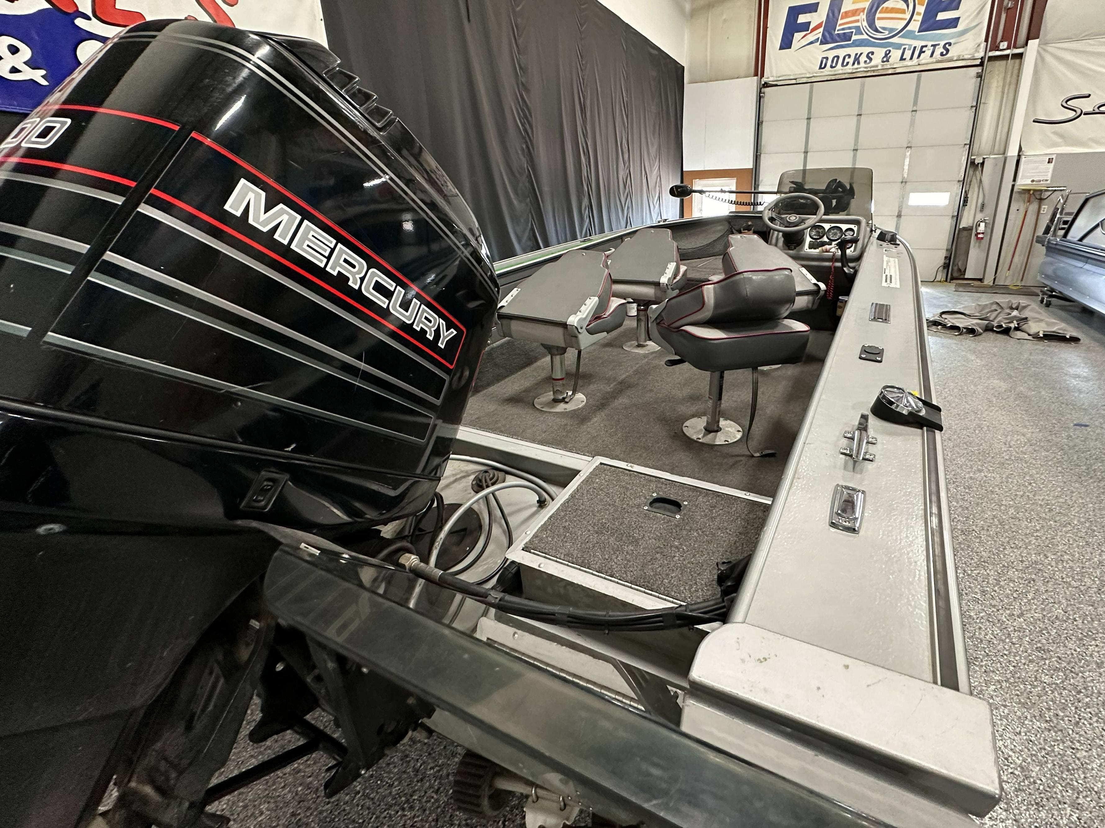1995 Lund 1650 DLX boat with Mercury engine in a garage setting.