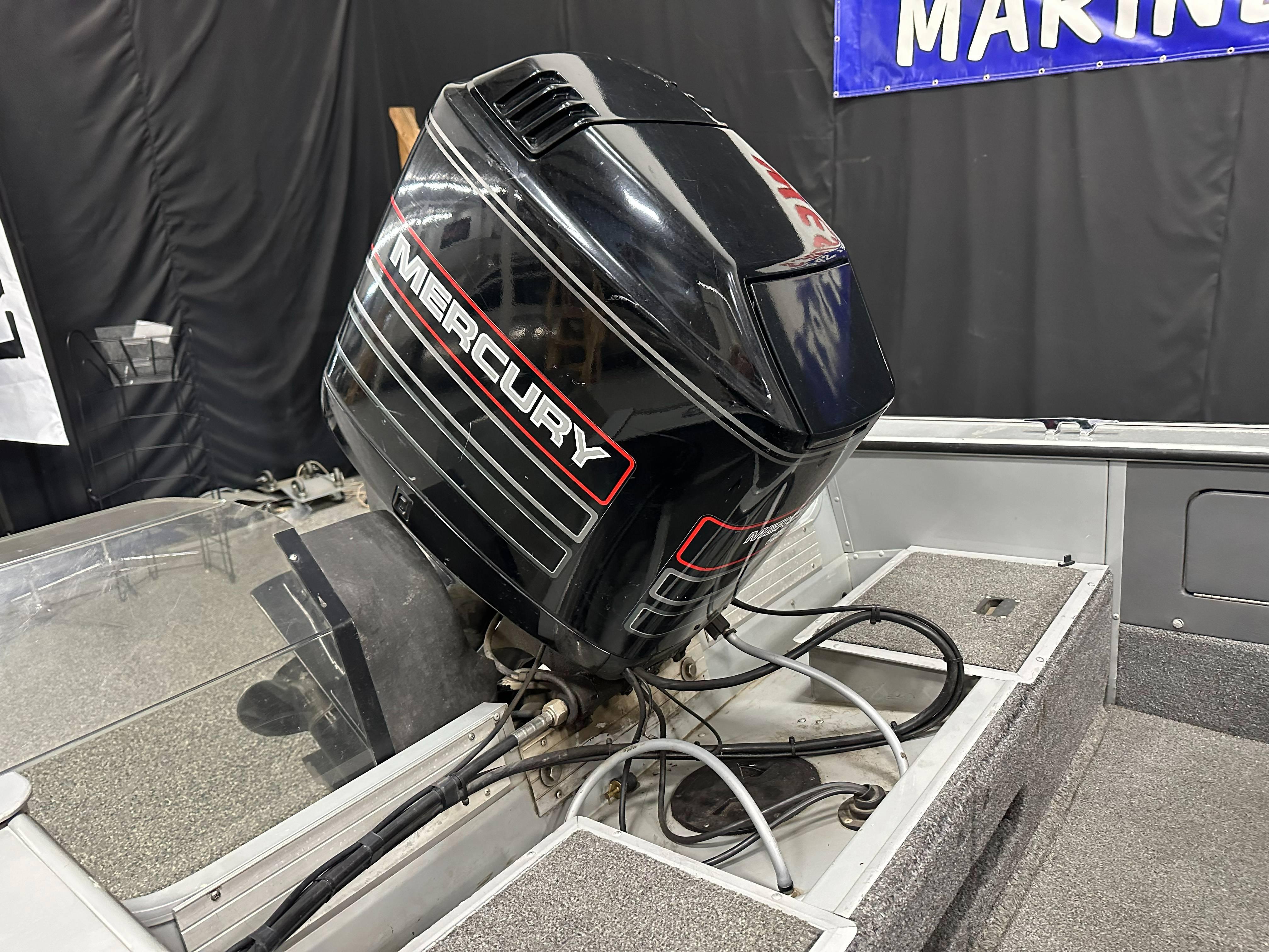1995 Lund 1650 DLX boat with Mercury outboard motor in a showroom.