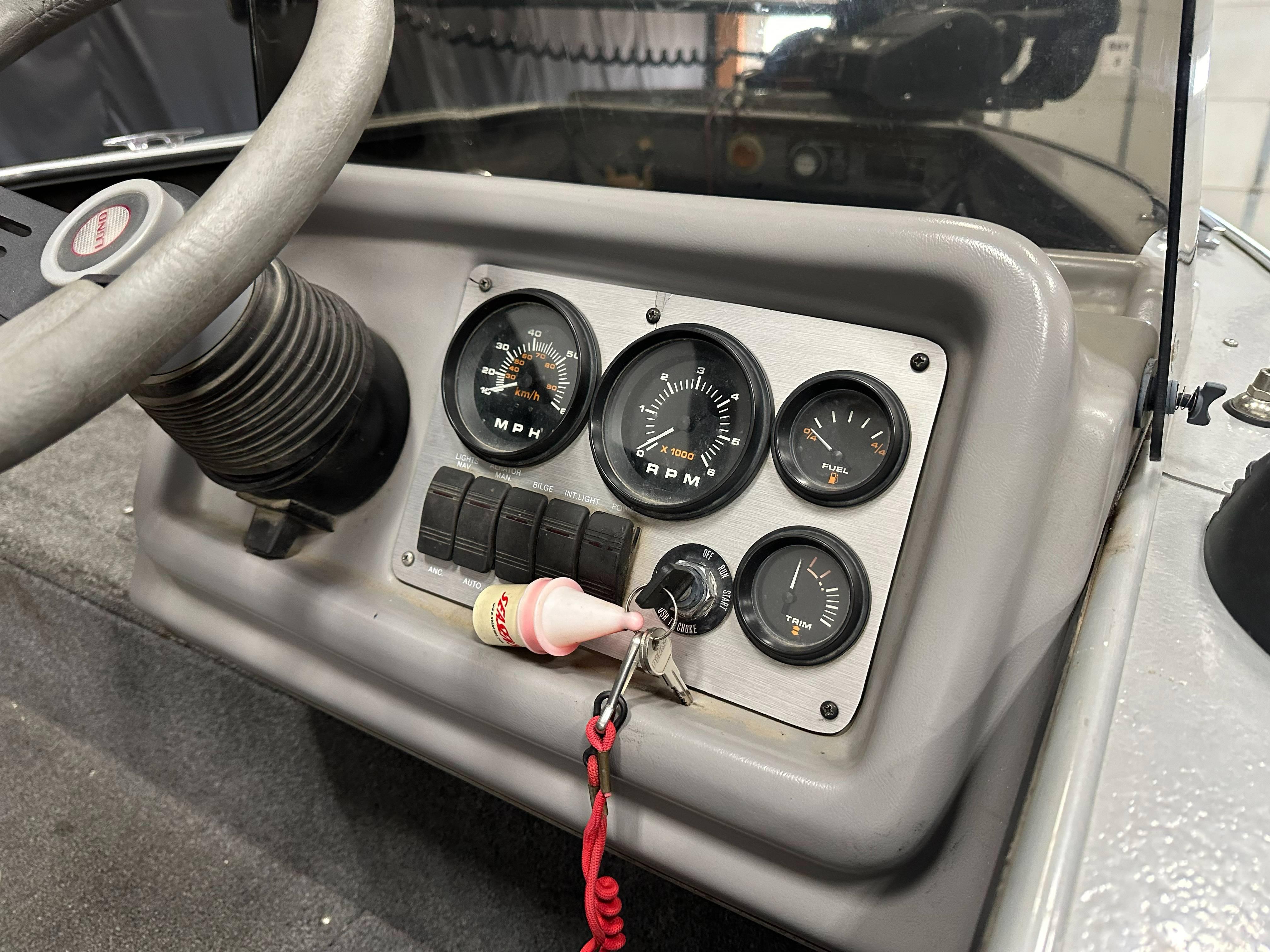 Dashboard of a 1995 Lund 1650 DLX boat with gauges and ignition keys.