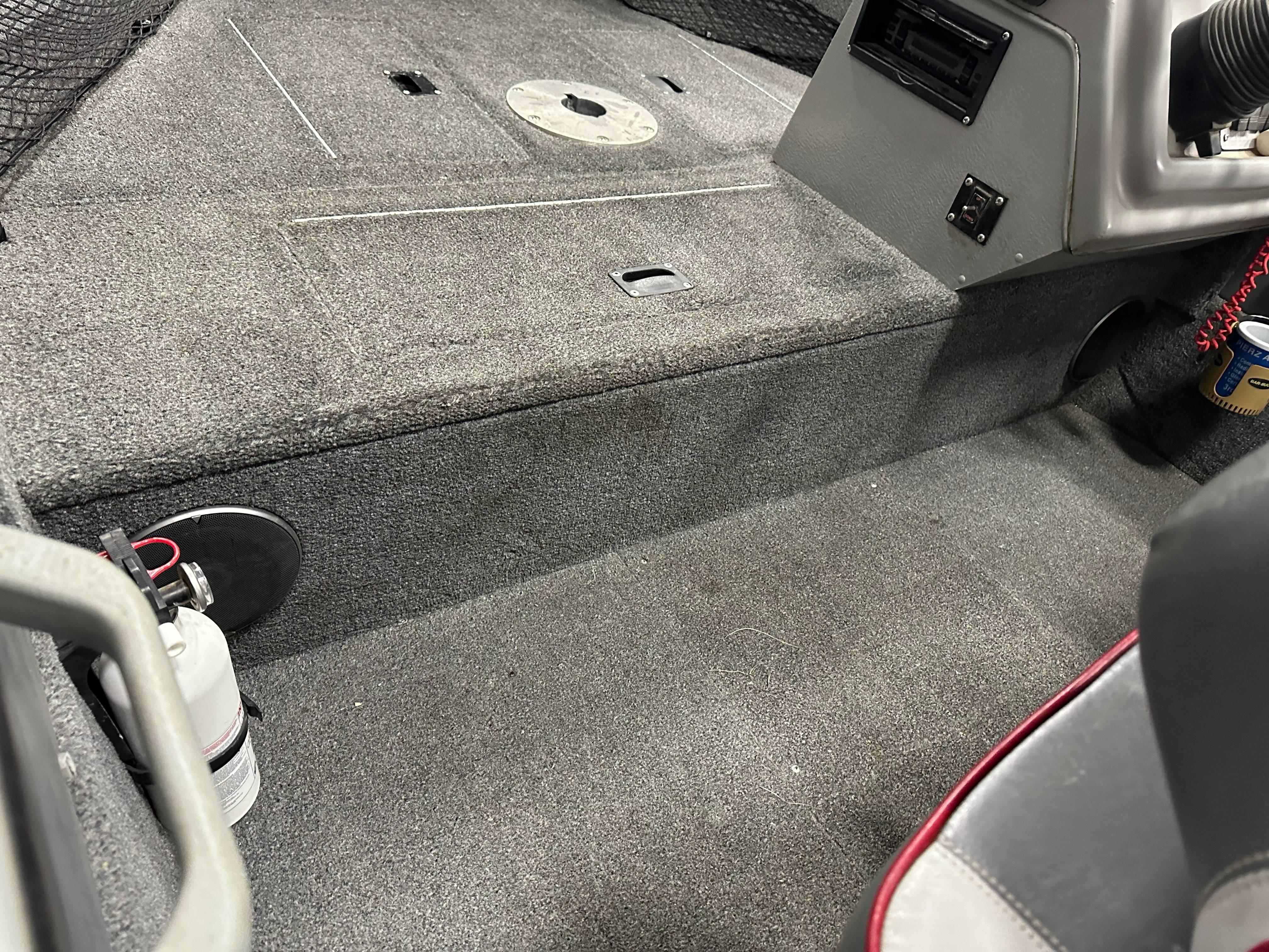 Interior of a 1995 Lund 1650 DLX boat, featuring carpeted flooring and control panel.