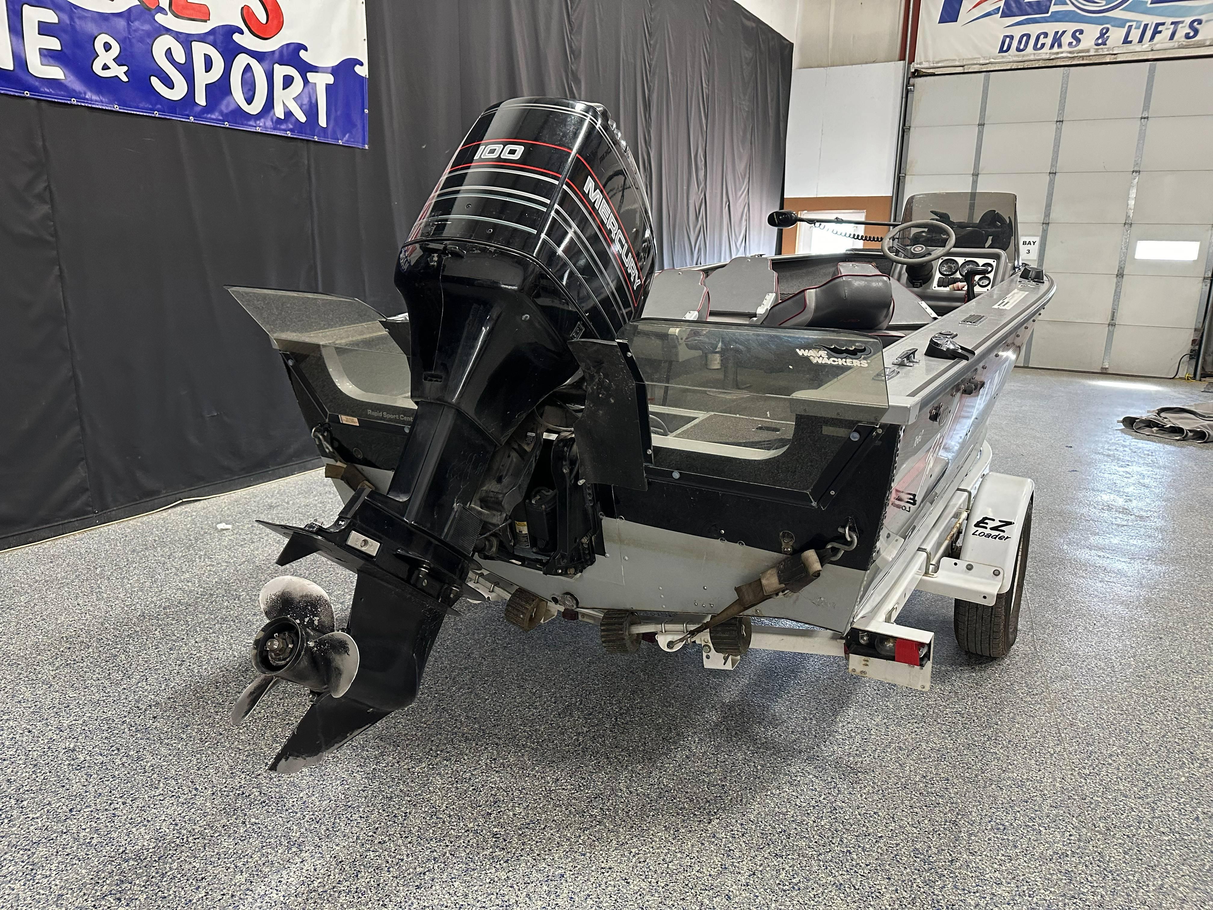 1995 Lund 1650 DLX boat with outboard motor on trailer in showroom.