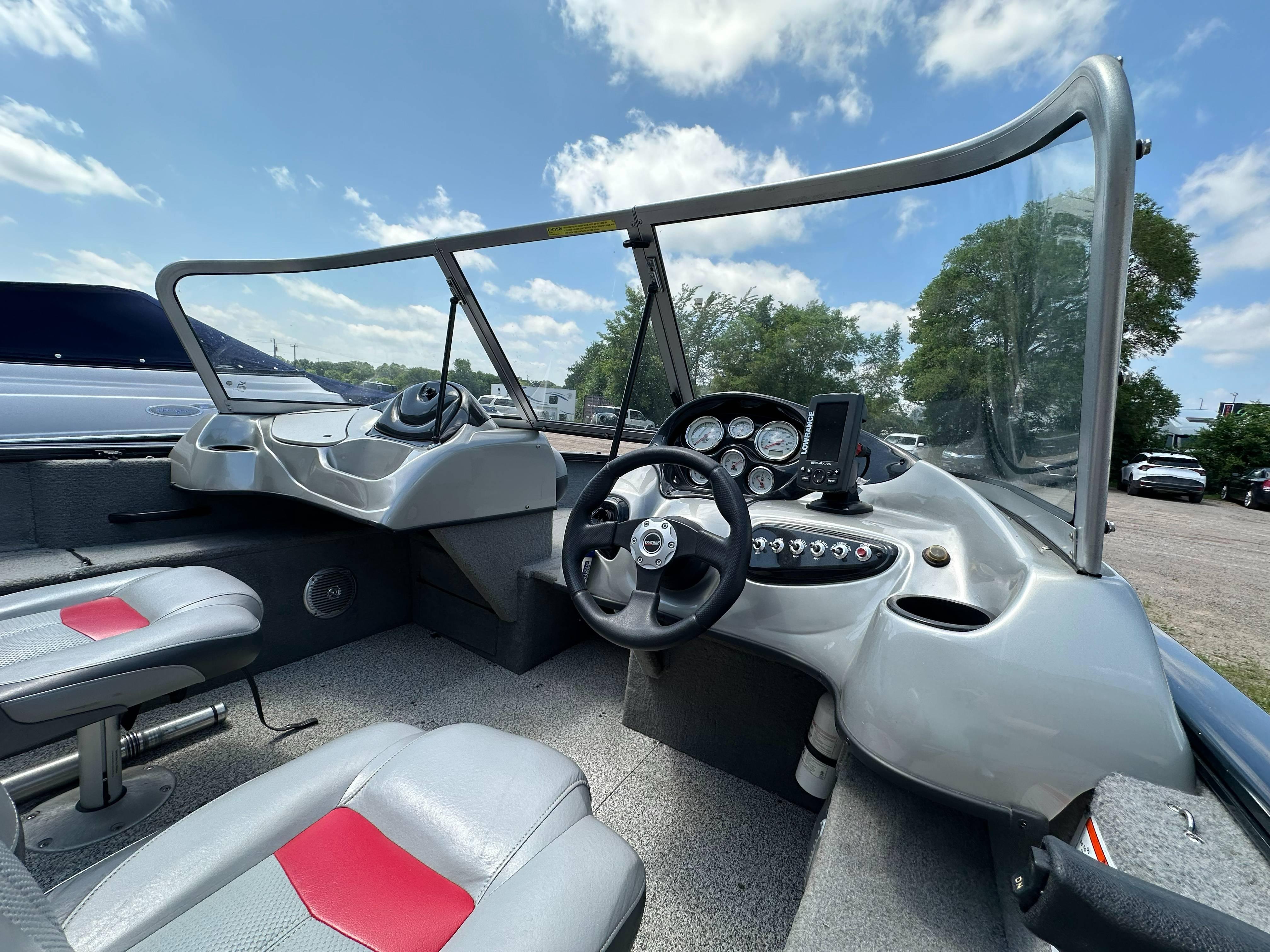 2013 Tracker Pro Guide V-175 WT boat interior with steering wheel and dashboard under blue sky.