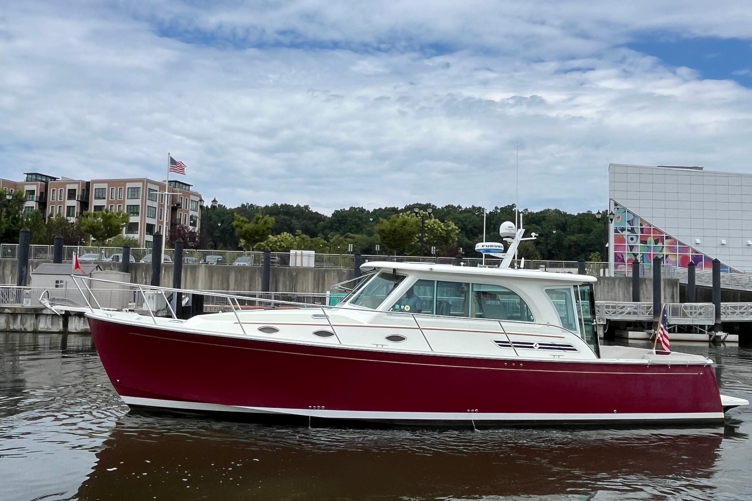 2017 Back Cove 41 boat with red hull docked near modern buildings.