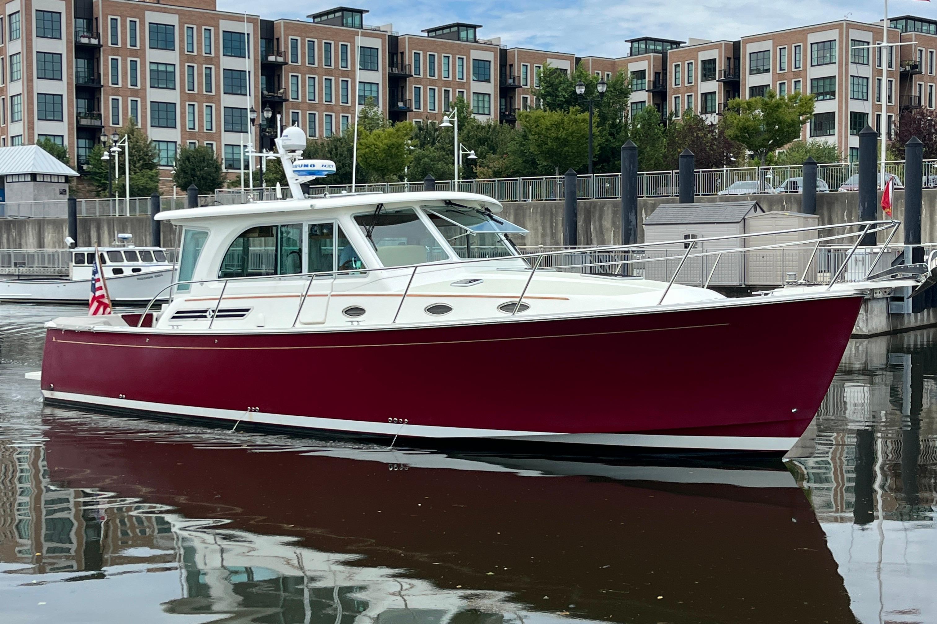 2017 Back Cove 41 boat with red hull docked in urban marina.