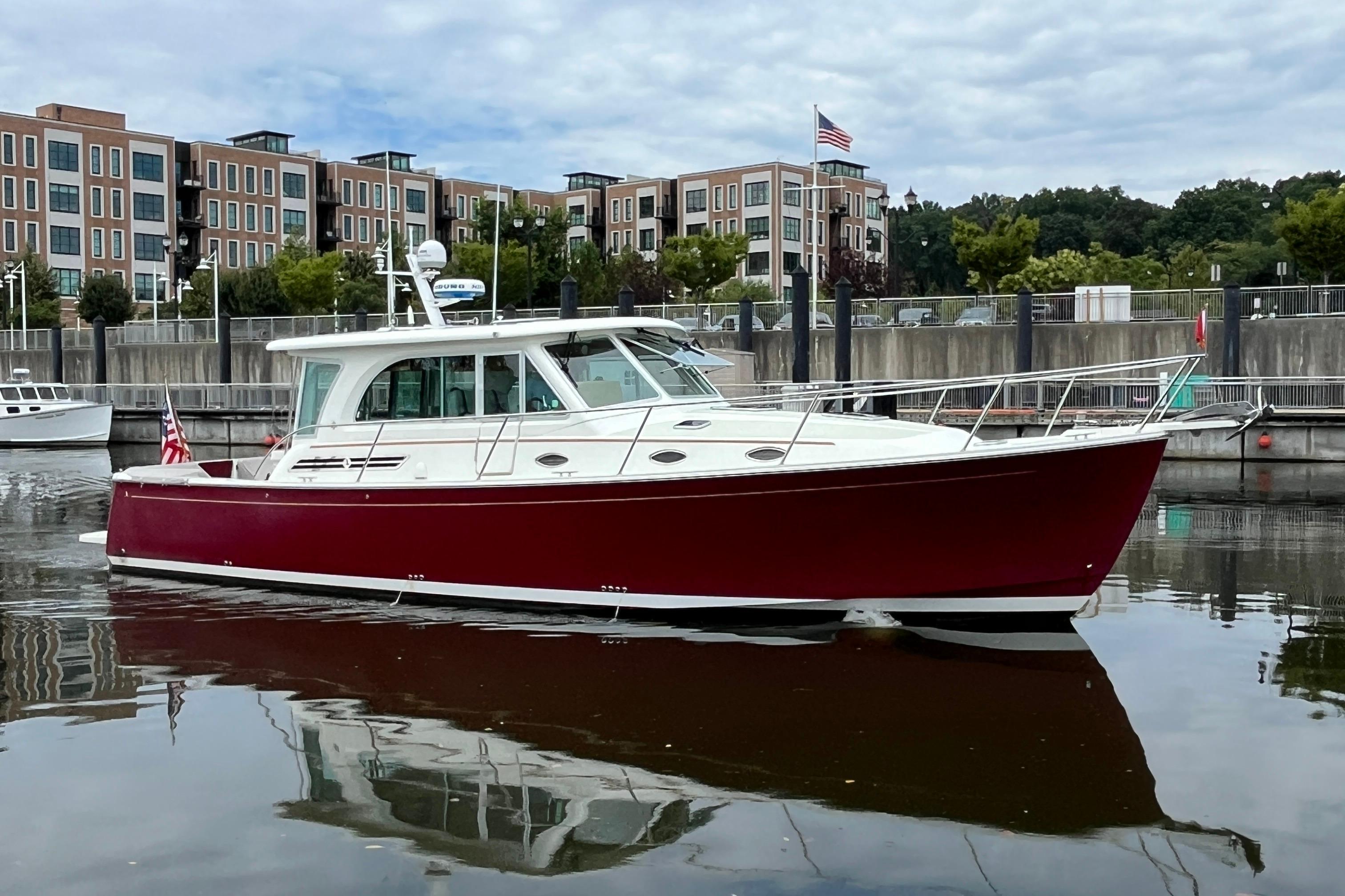 2017 Back Cove 41 boat with red hull docked in a marina, urban backdrop.