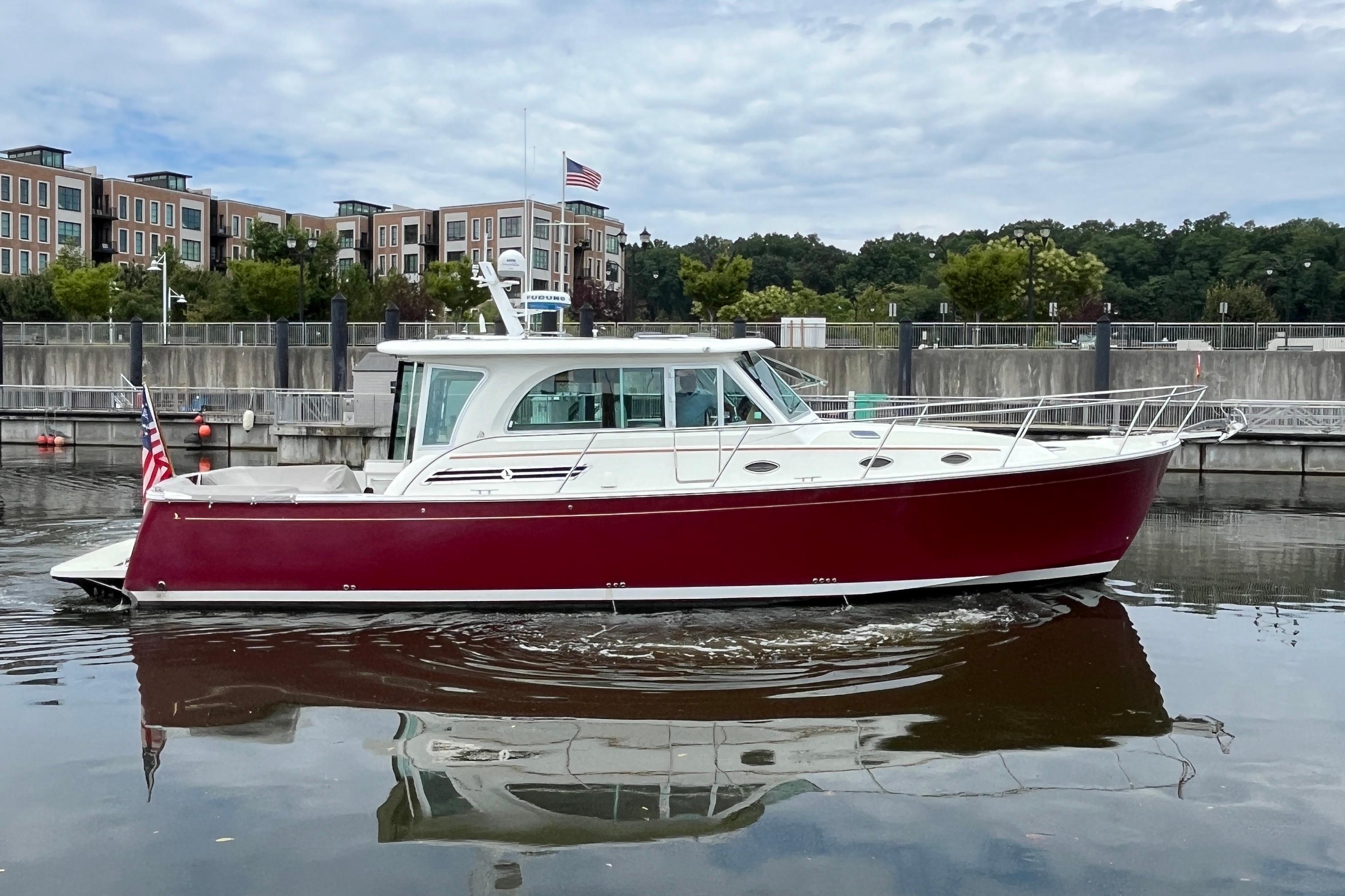 2017 Back Cove 41 boat with red hull, docked near modern buildings.