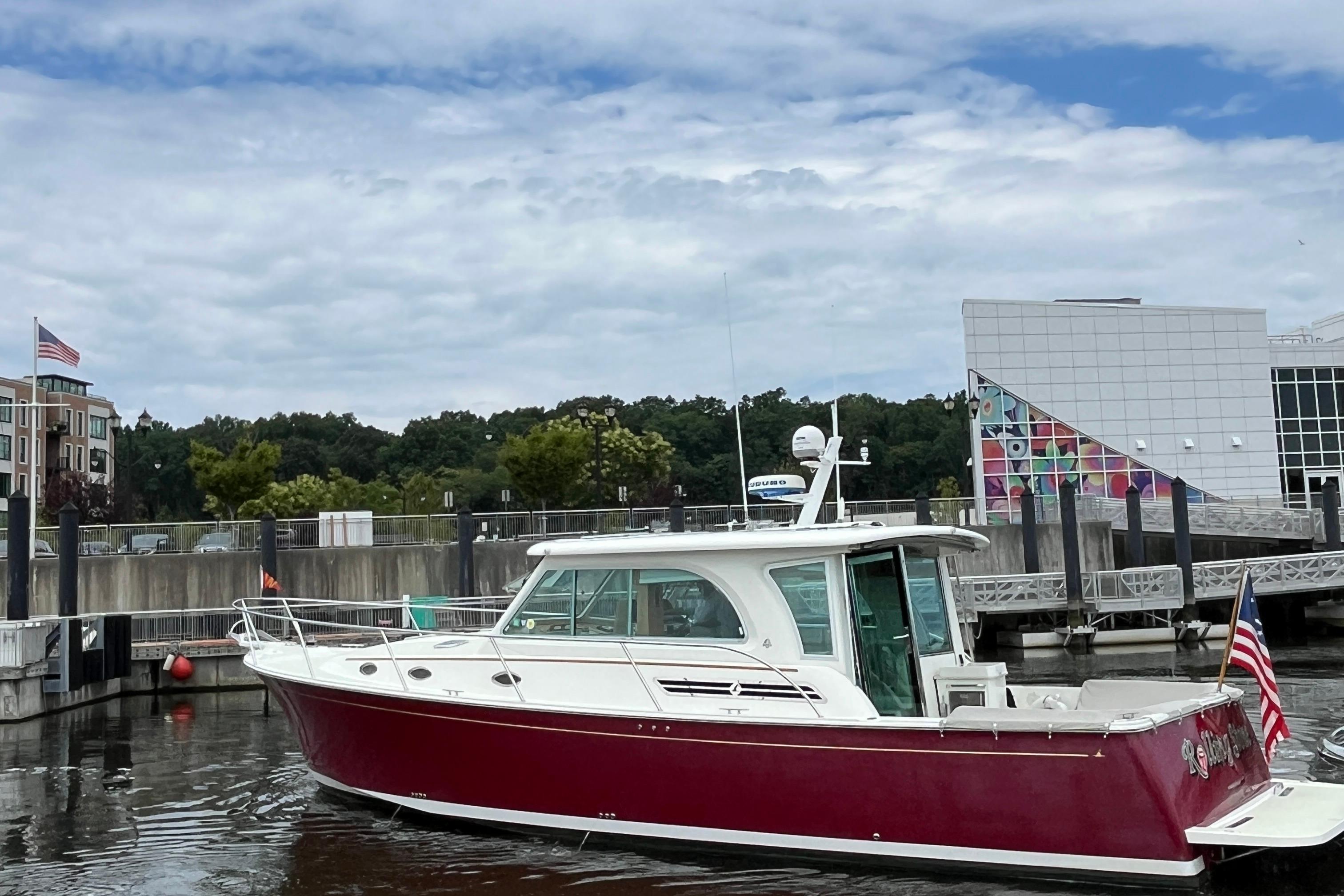 2017 Back Cove 41 boat with red hull docked in a marina, American flag displayed.