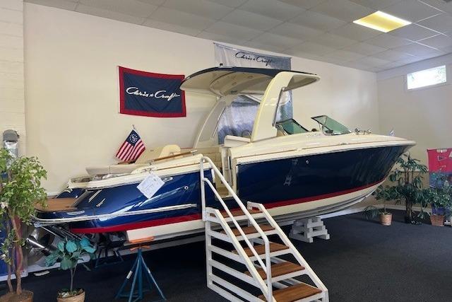 2025 Chris-Craft Launch 28 GT boat displayed indoors with American flag.