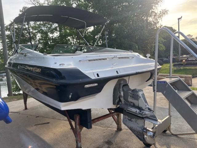 1999 Crownline 202 boat on stand, with canopy, near water and trees.