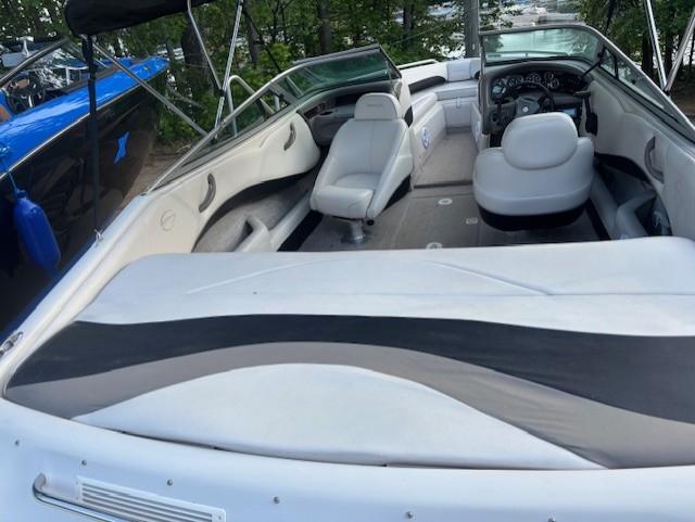1999 Crownline 202 boat interior with white seating and dashboard, parked outdoors.