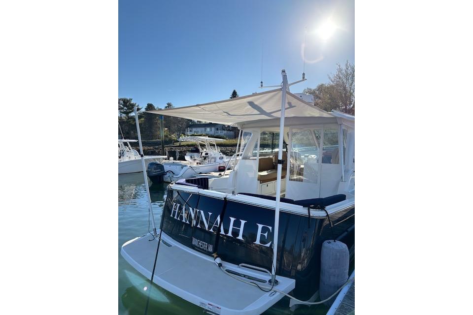 2018 Back Cove 30 boat docked under sunny sky, featuring canopy and seating area.