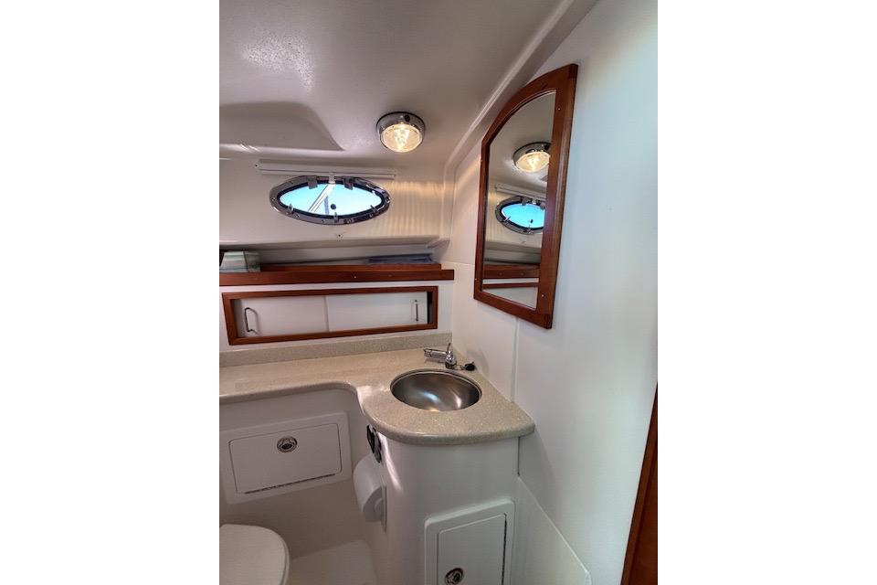 2018 Back Cove 30 yacht bathroom with sink, mirror, and porthole window.
