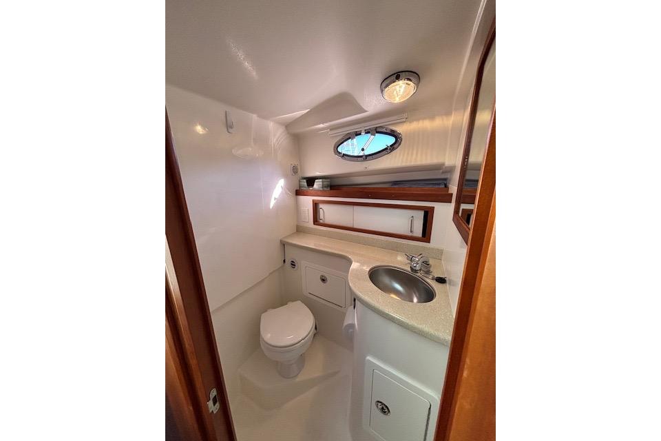 Compact bathroom in a 2018 Back Cove 30 boat, featuring a toilet, sink, and storage.