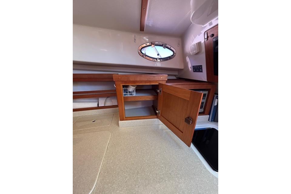 Interior of 2018 Back Cove 30 boat with open wooden cabinet and porthole window.