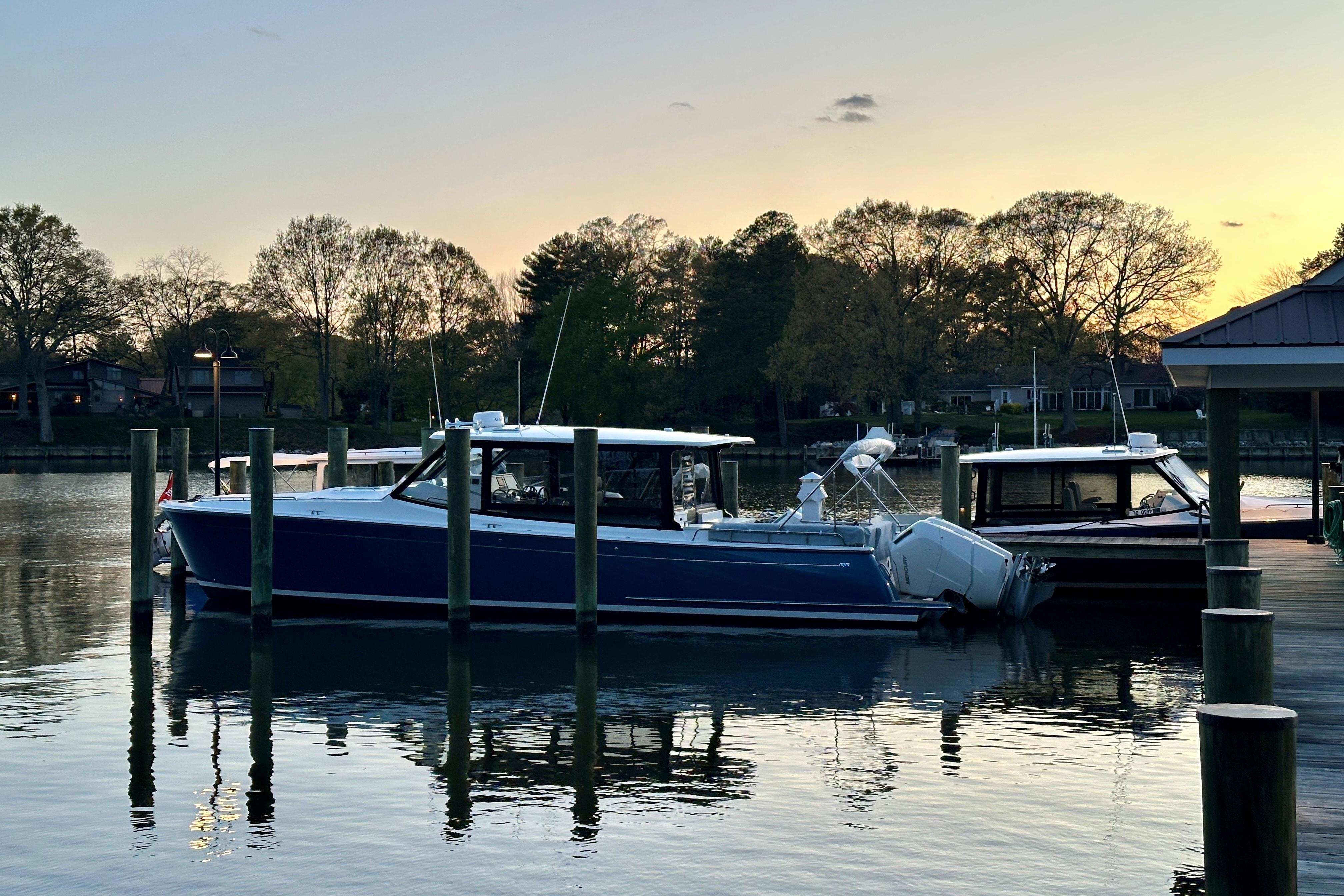 2025 MJM 4 boat docked at sunset, surrounded by calm water and trees.