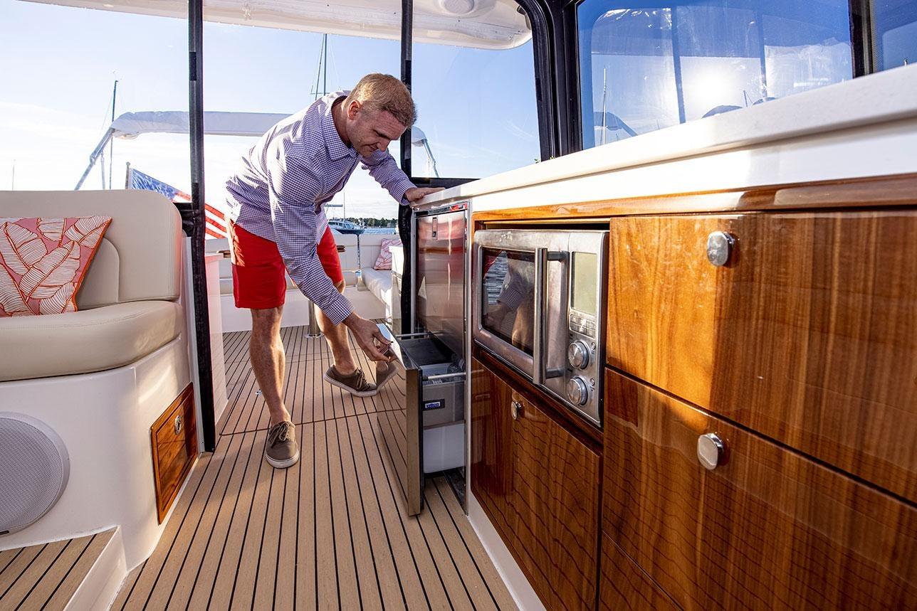Man using a drawer on a 2025 MJM 4 yachtu0027s deck kitchen.