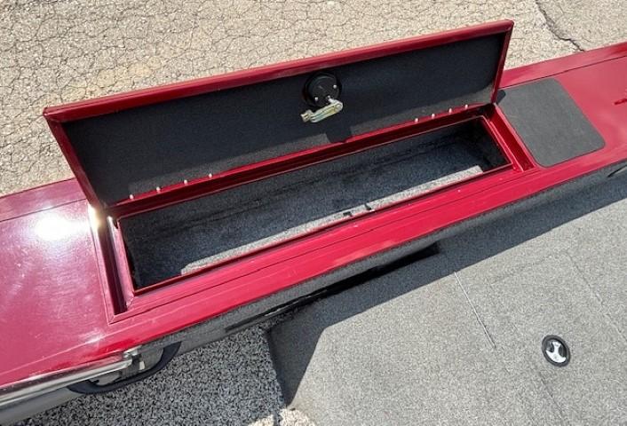 Open storage compartment on 2015 Tracker Targa V-18 Combo boat, red exterior, gray interior.