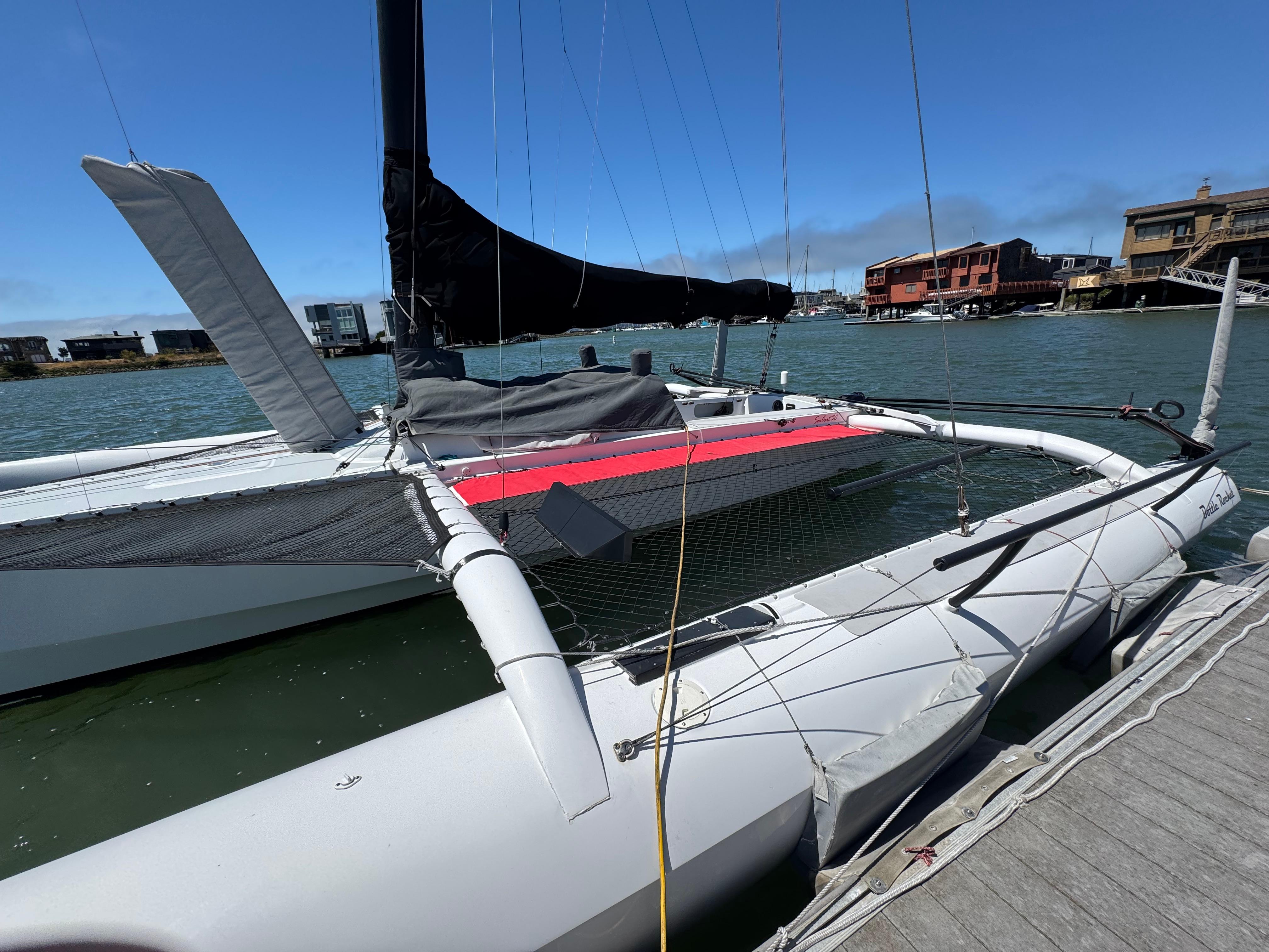 2015 Marstrom Seacart 30 trimaran docked by the waterfront on a sunny day.
