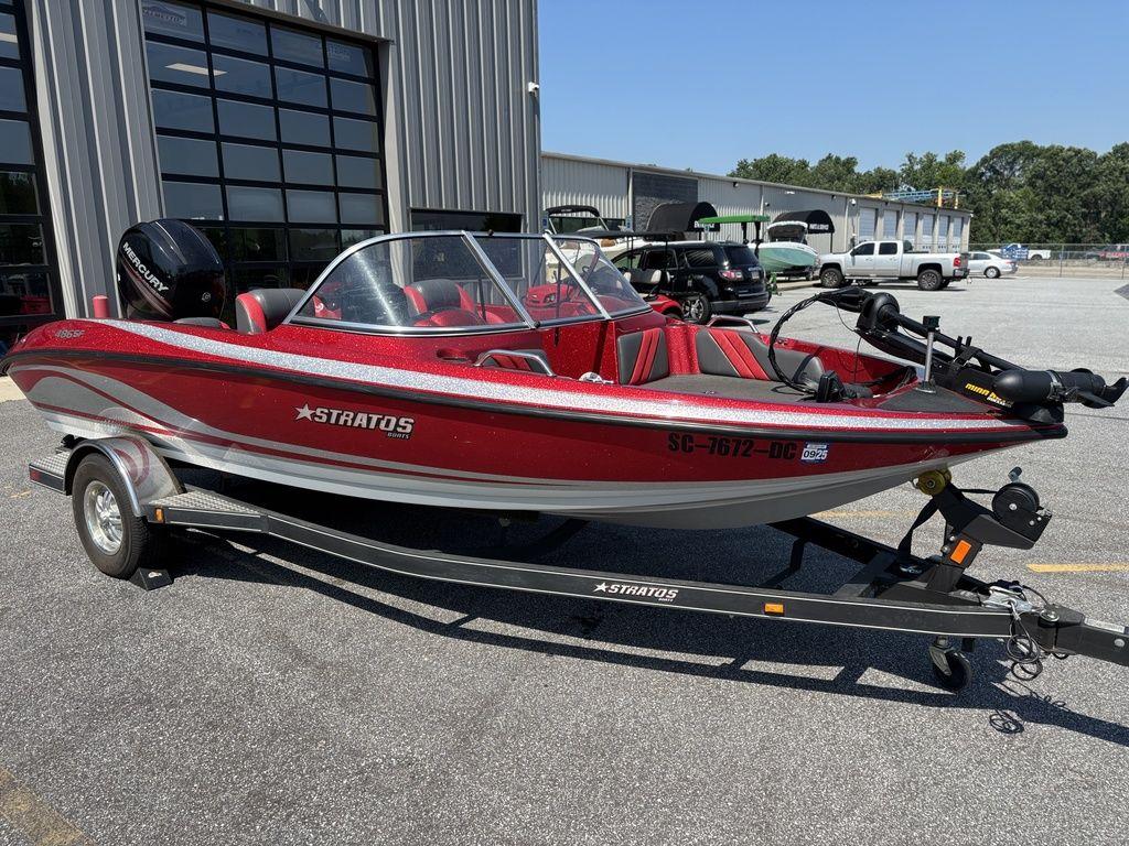 Red 2013 Stratos 486 SF boat on trailer, parked outside a building.