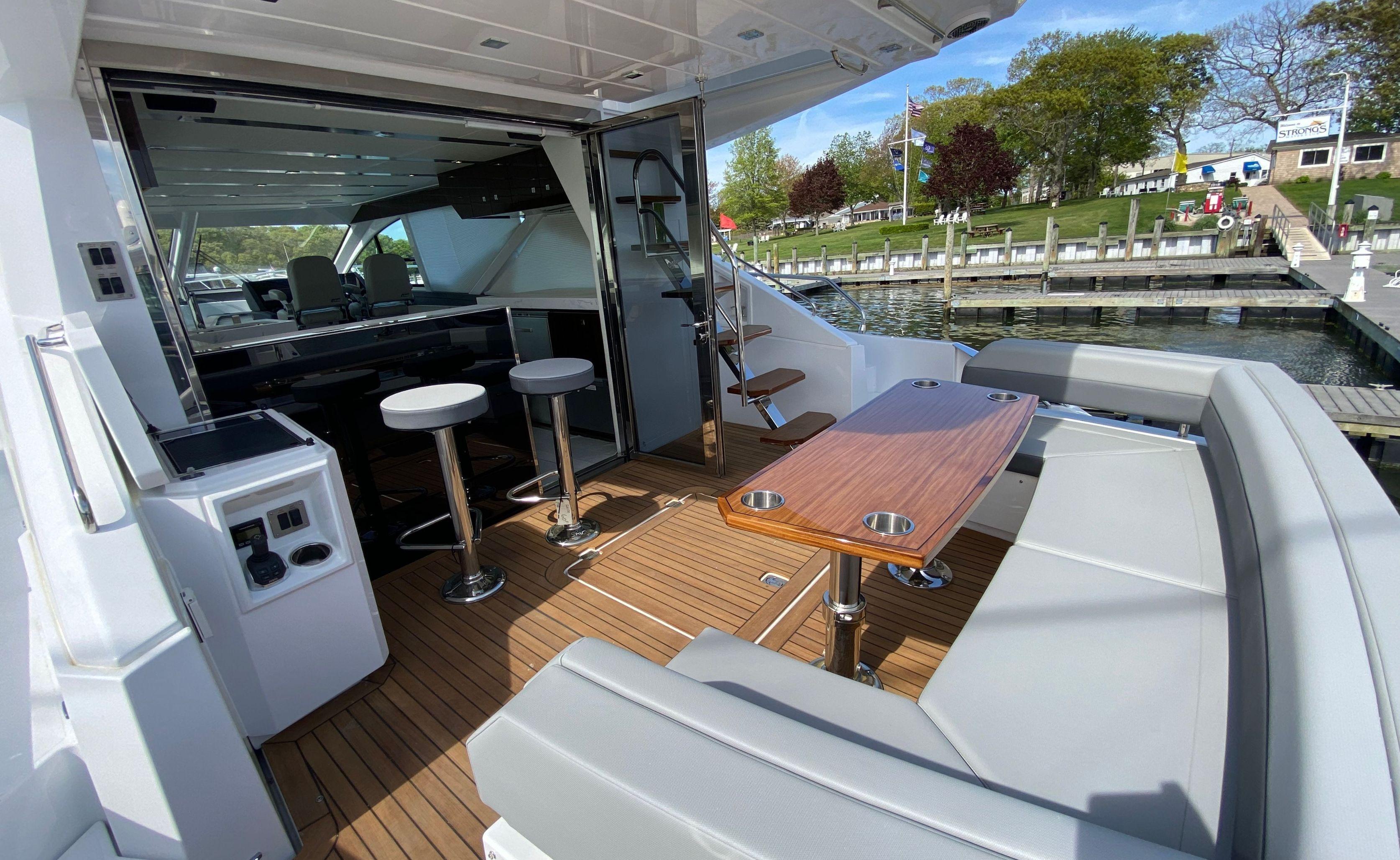 Cruisers Yachts-60 Fly 2022-RADIANT NY-US-2022 Cruisers Yachts 60 Fly deck with seating, table, and bar stools, docked by the water.-9652120 | Thumbnail
