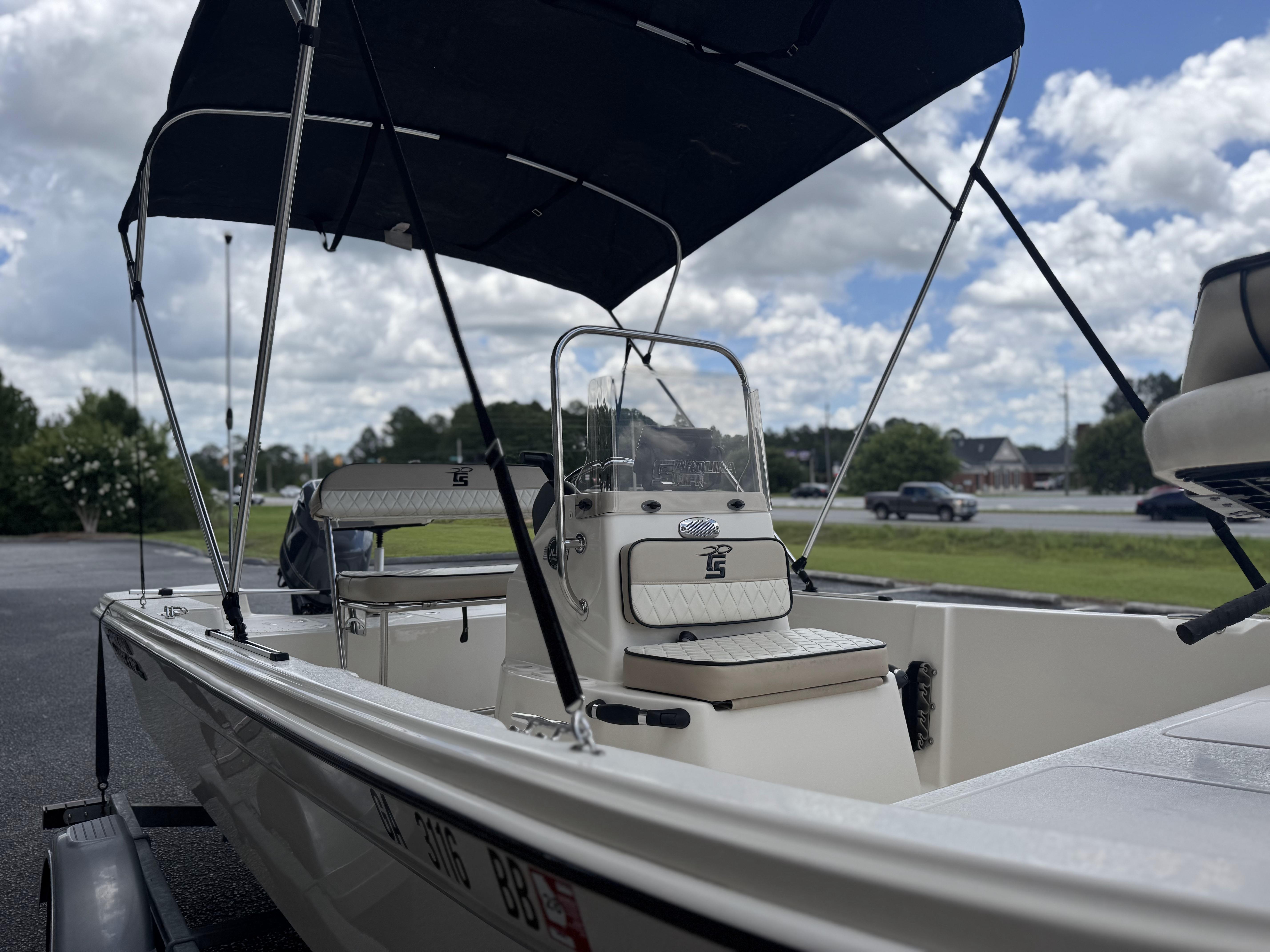 2020 Carolina Skiff 178JLS boat with canopy, parked outdoors under a cloudy sky.
