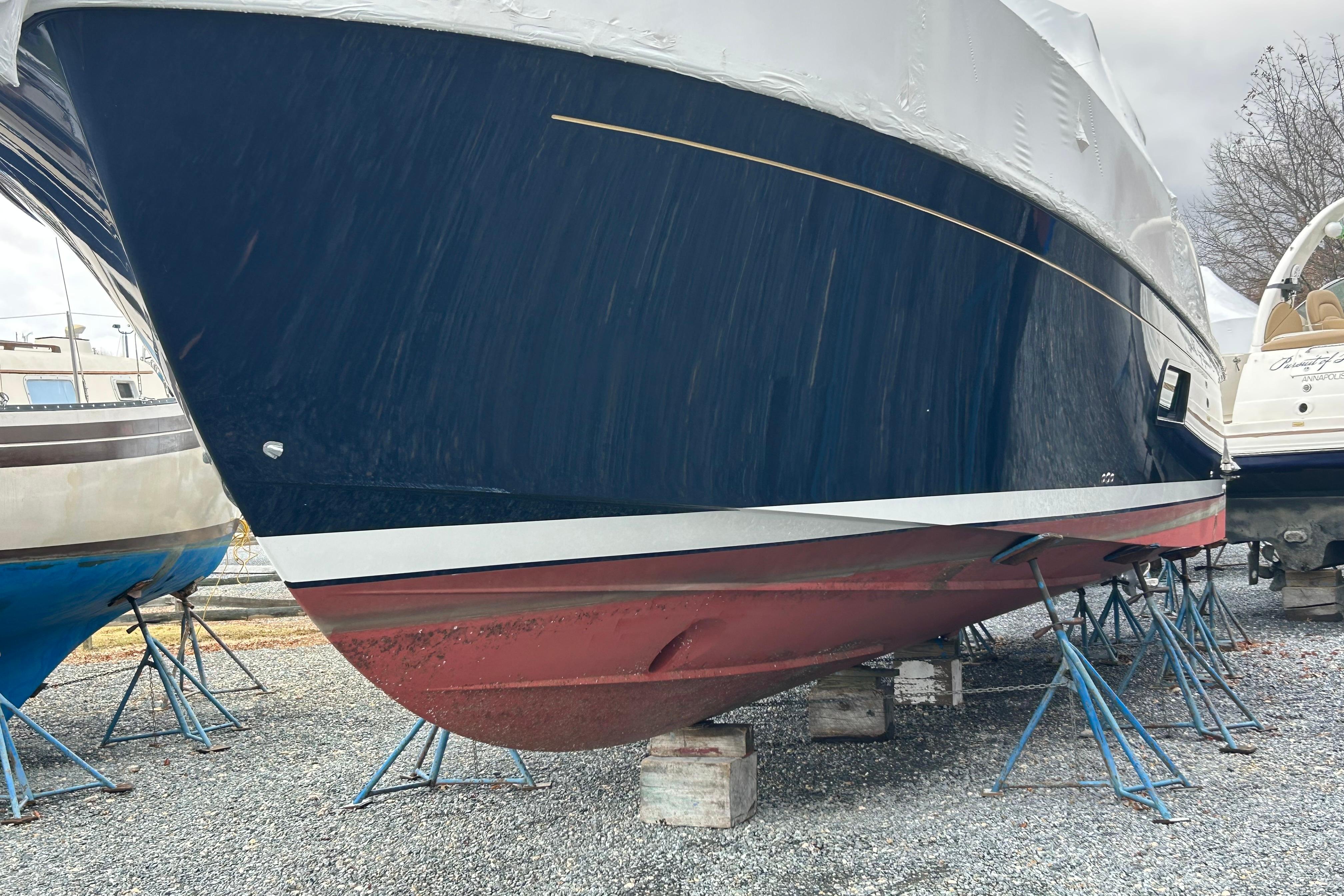 2023 Back Cove 39O boat on stands, flag blue hull, red bottom, outdoor storage.